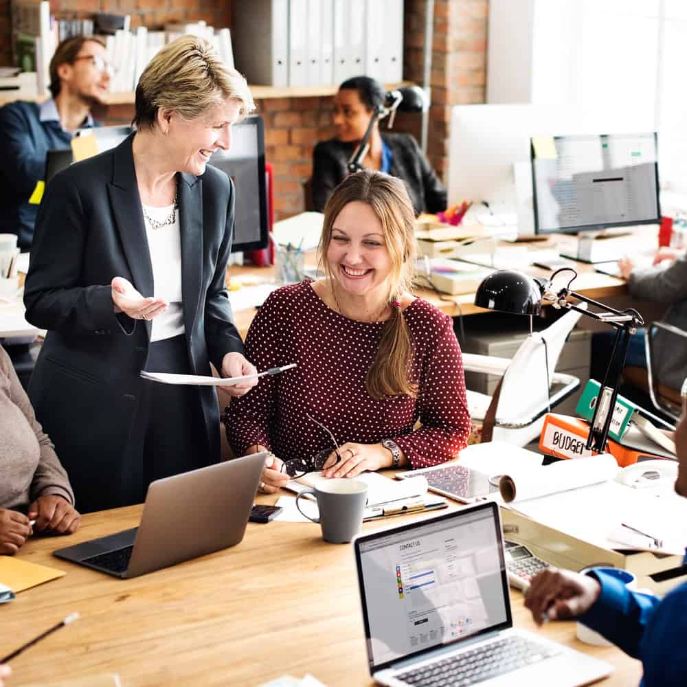 Manager and team members smiling and collaborating in a busy office