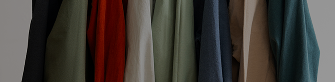 A row of hanging coats and jackets in various colors including black, green, red, blue, beige, and teal.