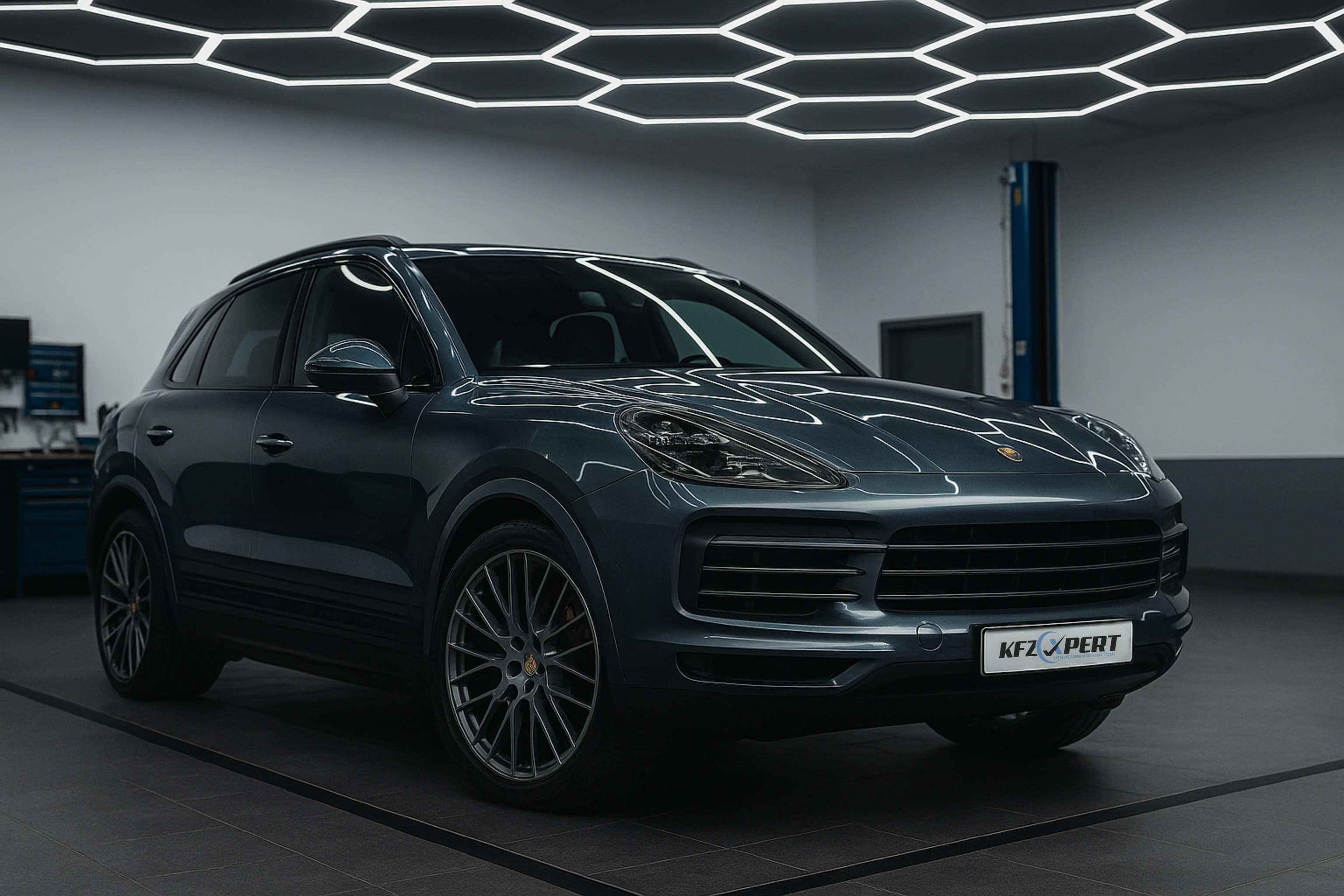 Dark gray luxury SUV parked indoors with modern hexagonal ceiling lights reflecting on it.