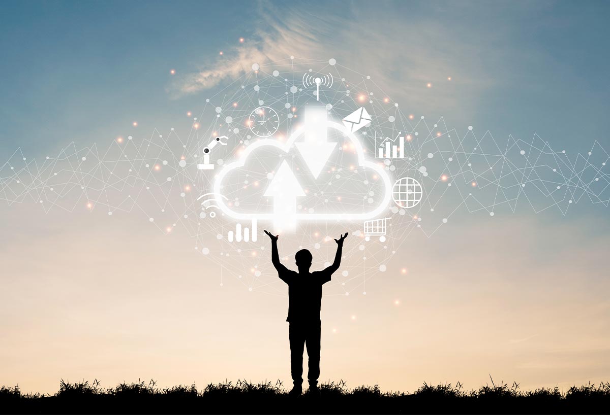 Silhouette of a person standing outdoors with hands raised towards a glowing cloud icon surrounded by digital technology and data symbols against a sunset sky.