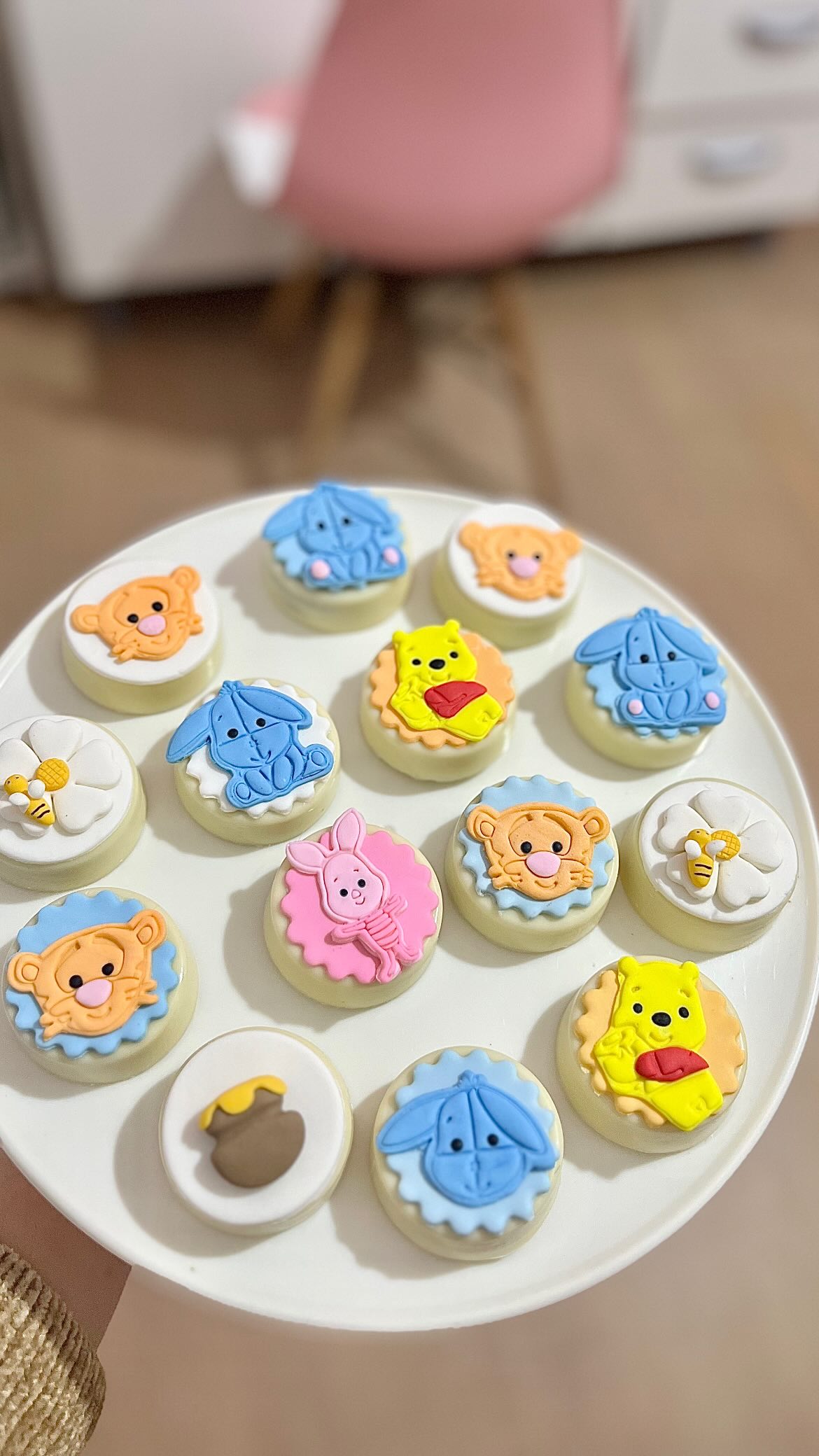 Plate of decorated cookies featuring Winnie the Pooh characters, including Pooh, Tigger, Piglet, Eeyore, bees, and a honey pot.
