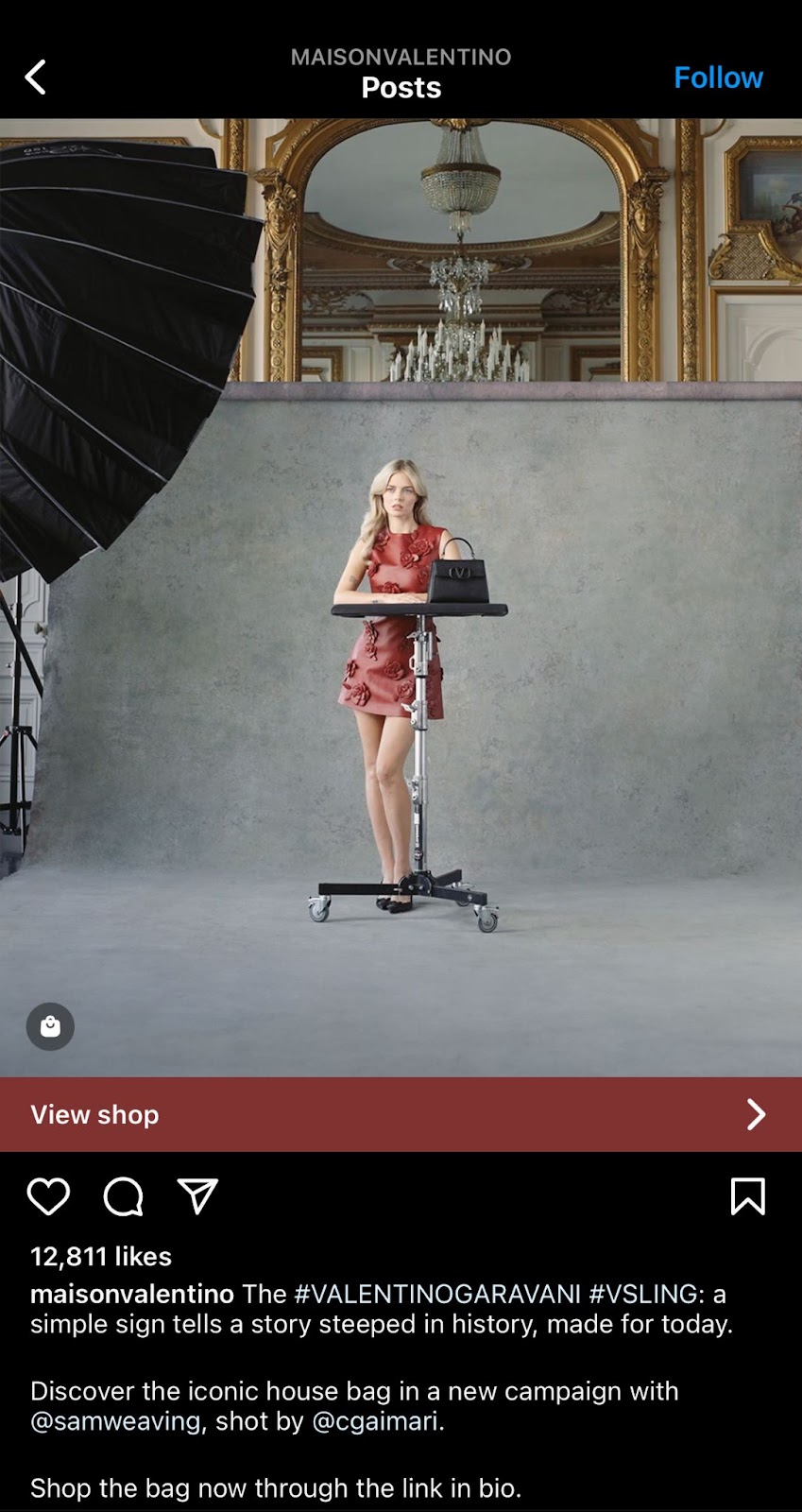 Women modeling for valentino wearing red dress and black bag looking at camera