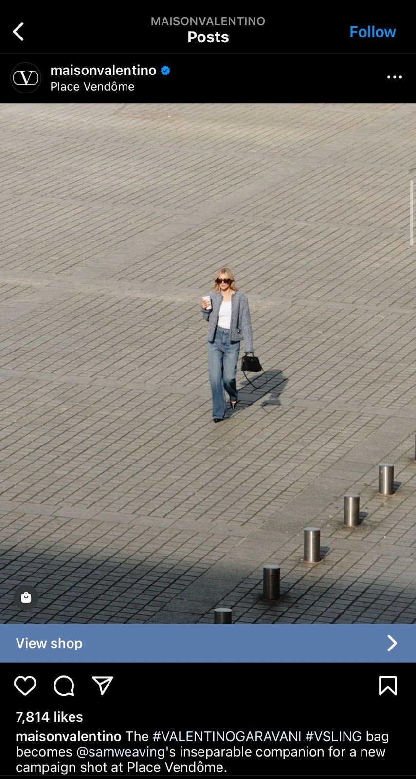 Women modeling for valentino wearing a blazer and jeans holding a brown bag and a drink in her hand