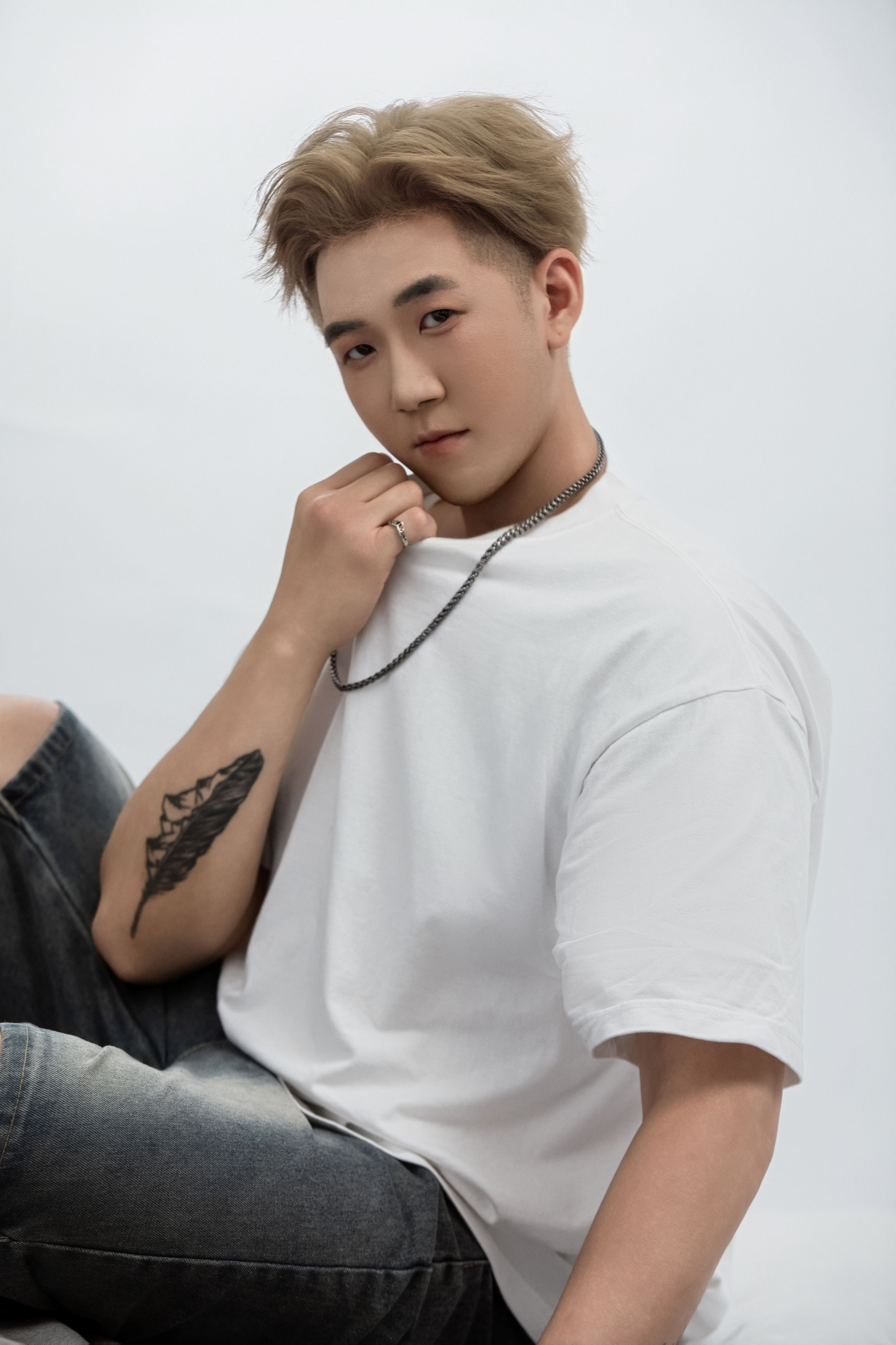 A man sits up, his hand resting in front of his neck.