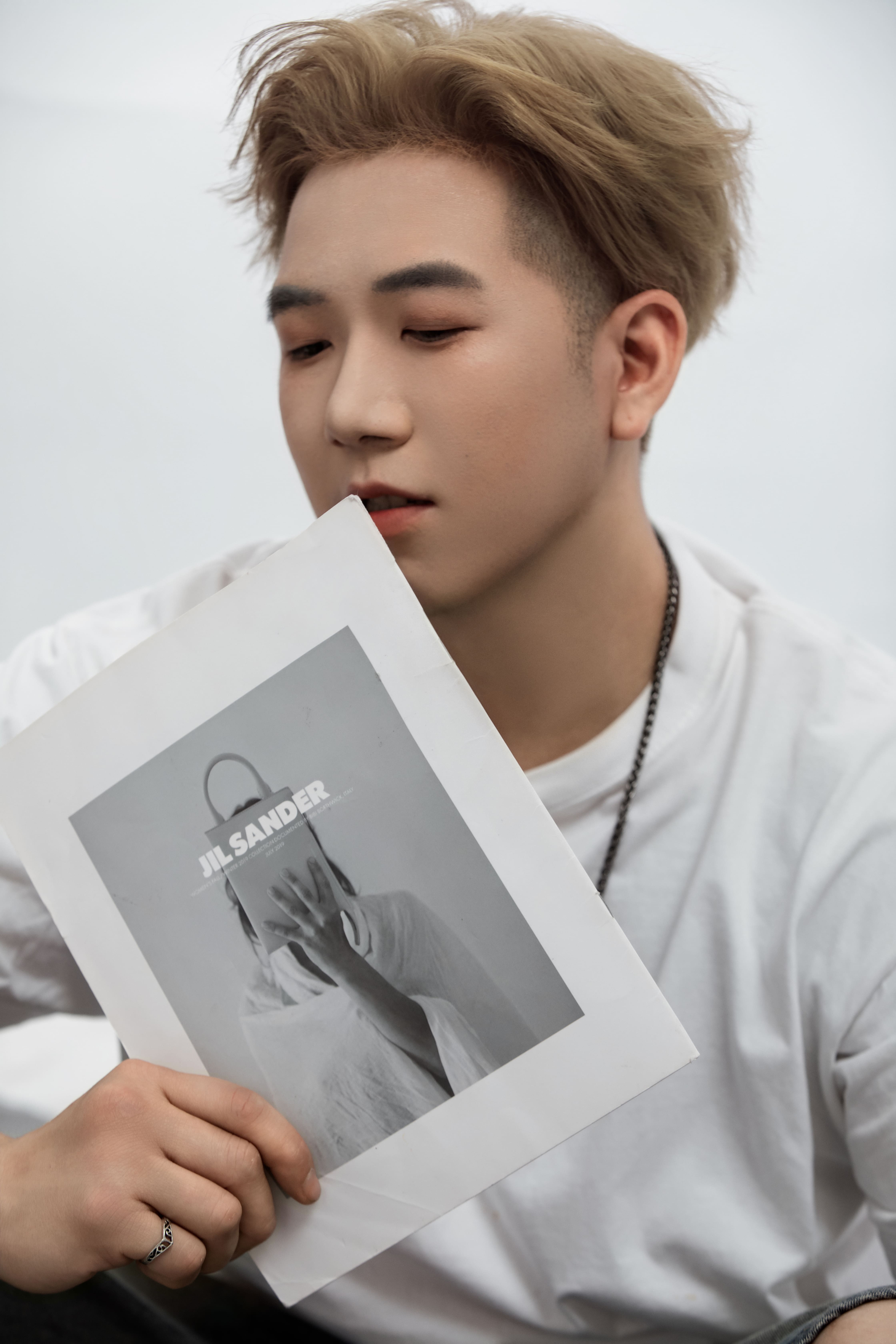 A man holds a Jil Sander poster close to his chest, his eyes gently closed.