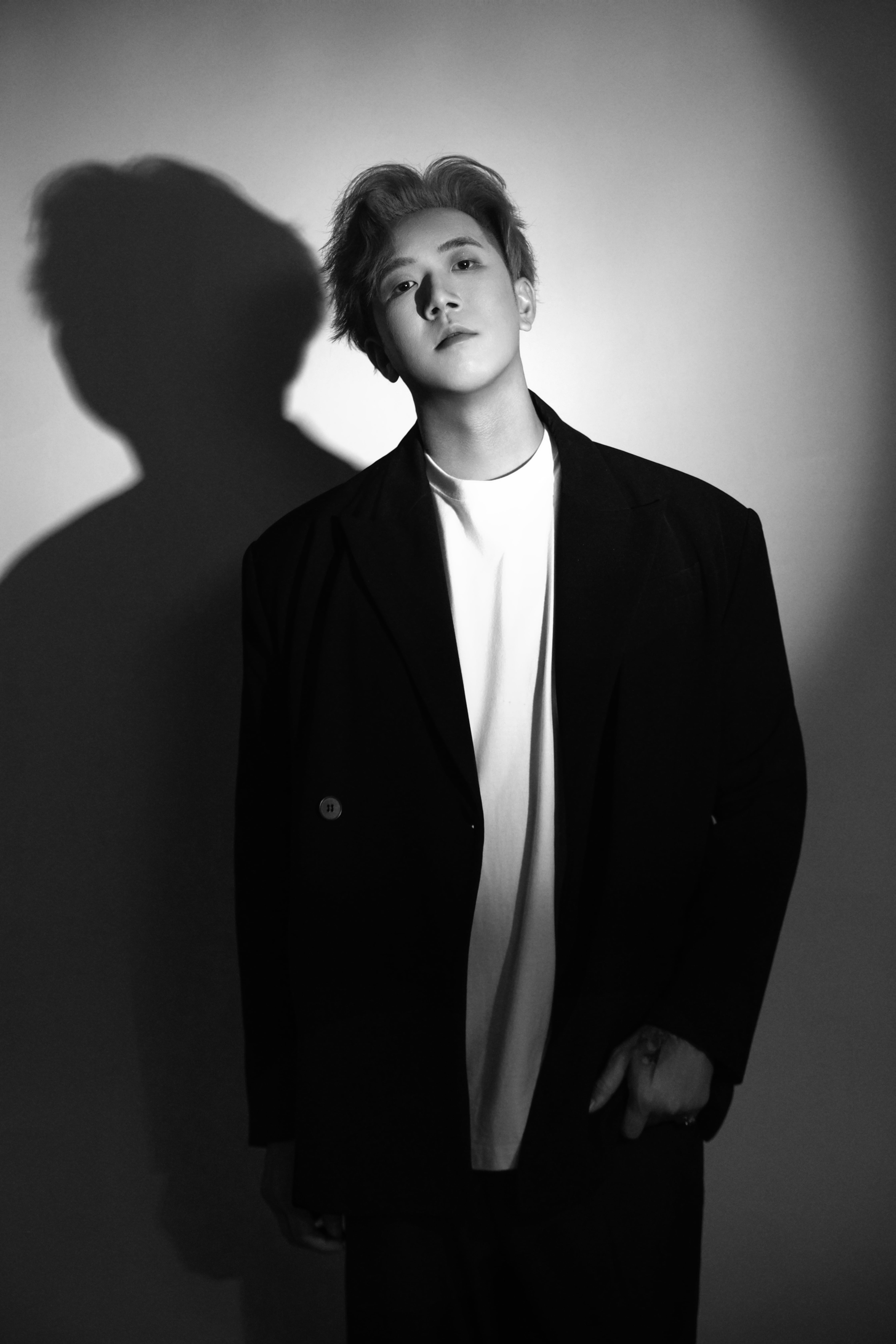 A man stands upright in black and white, his neck tilted slightly to the right.