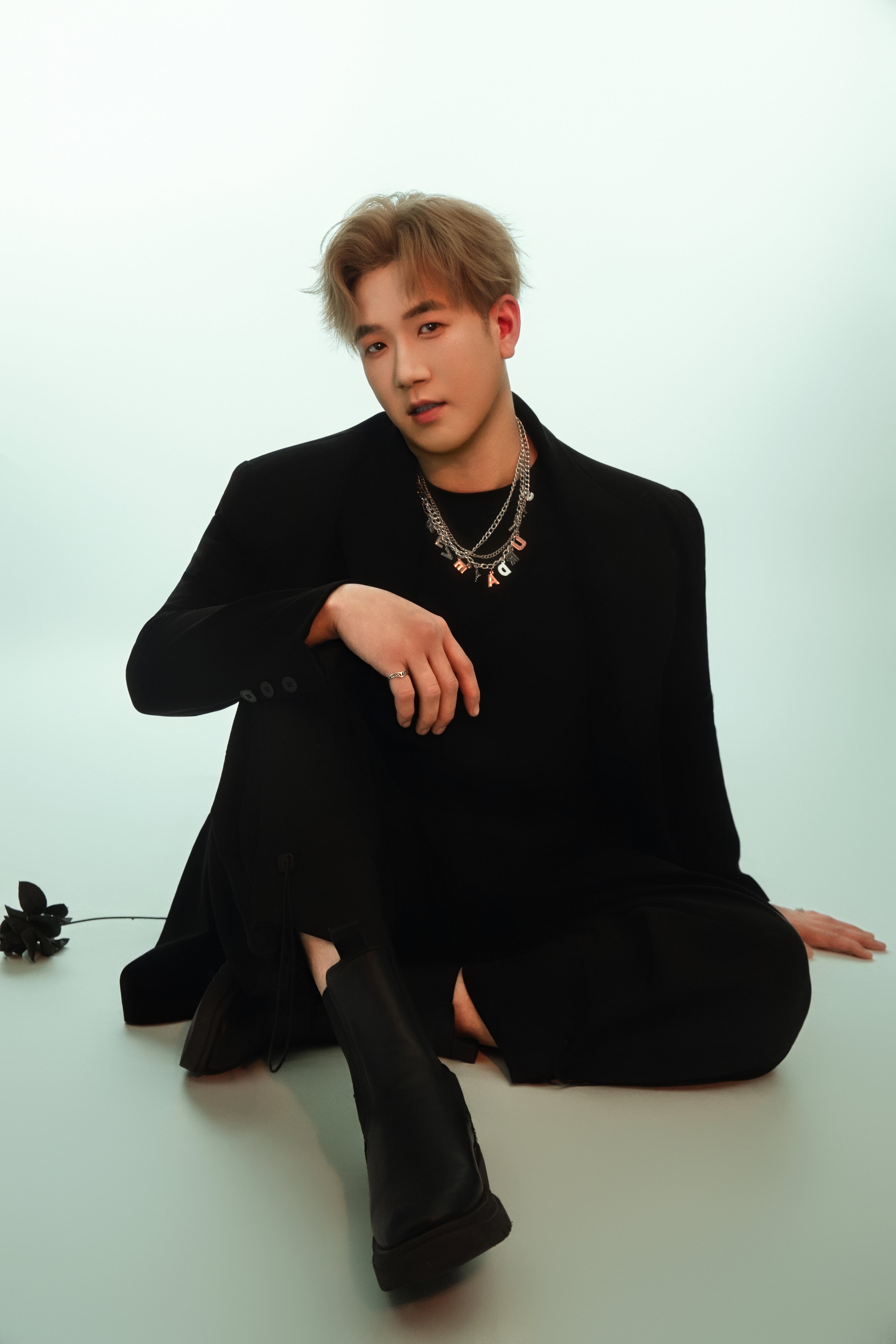 Seated on the floor, a man is illuminated by emerald hues.