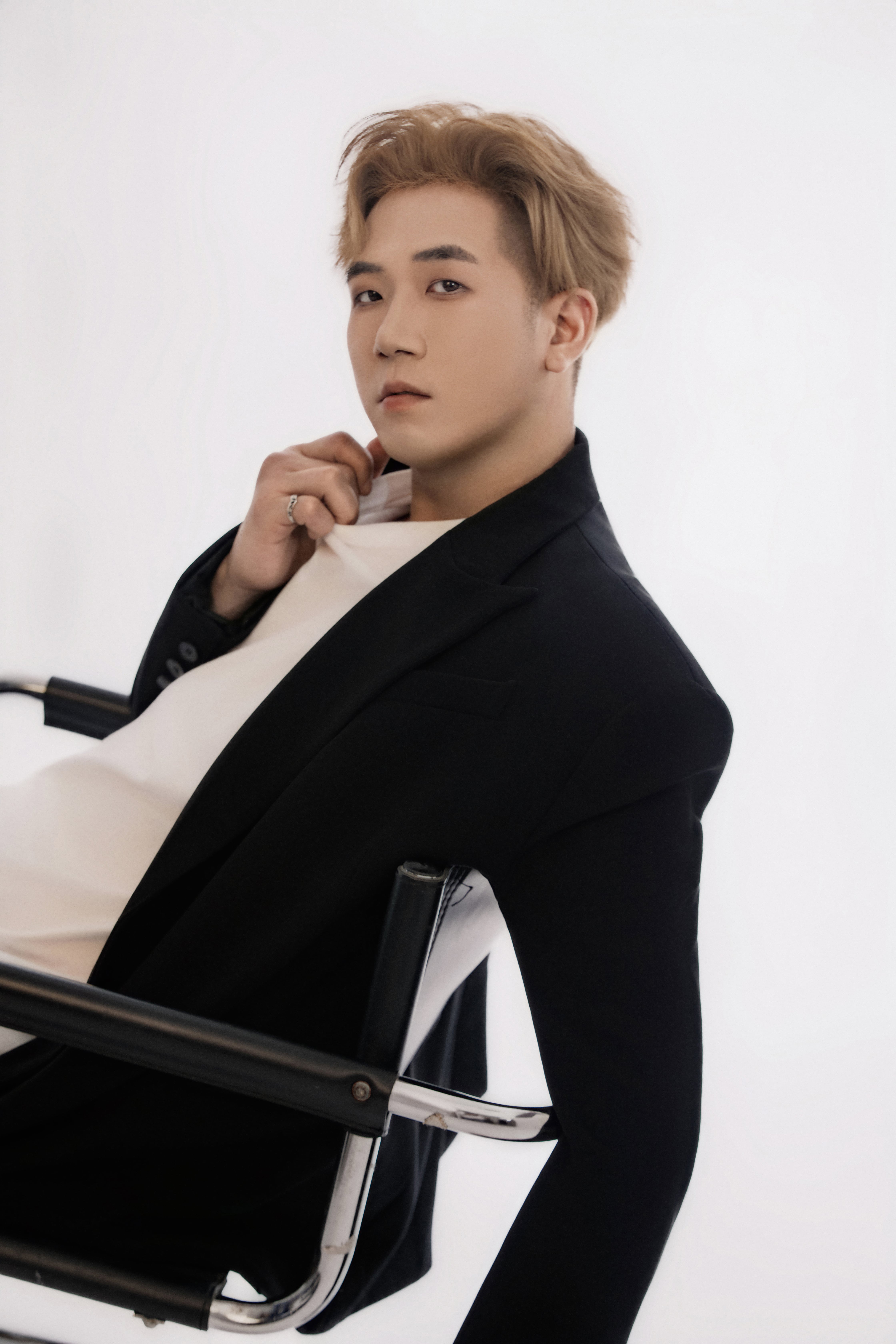 A man leans back on a chair and looks directly into the camera.