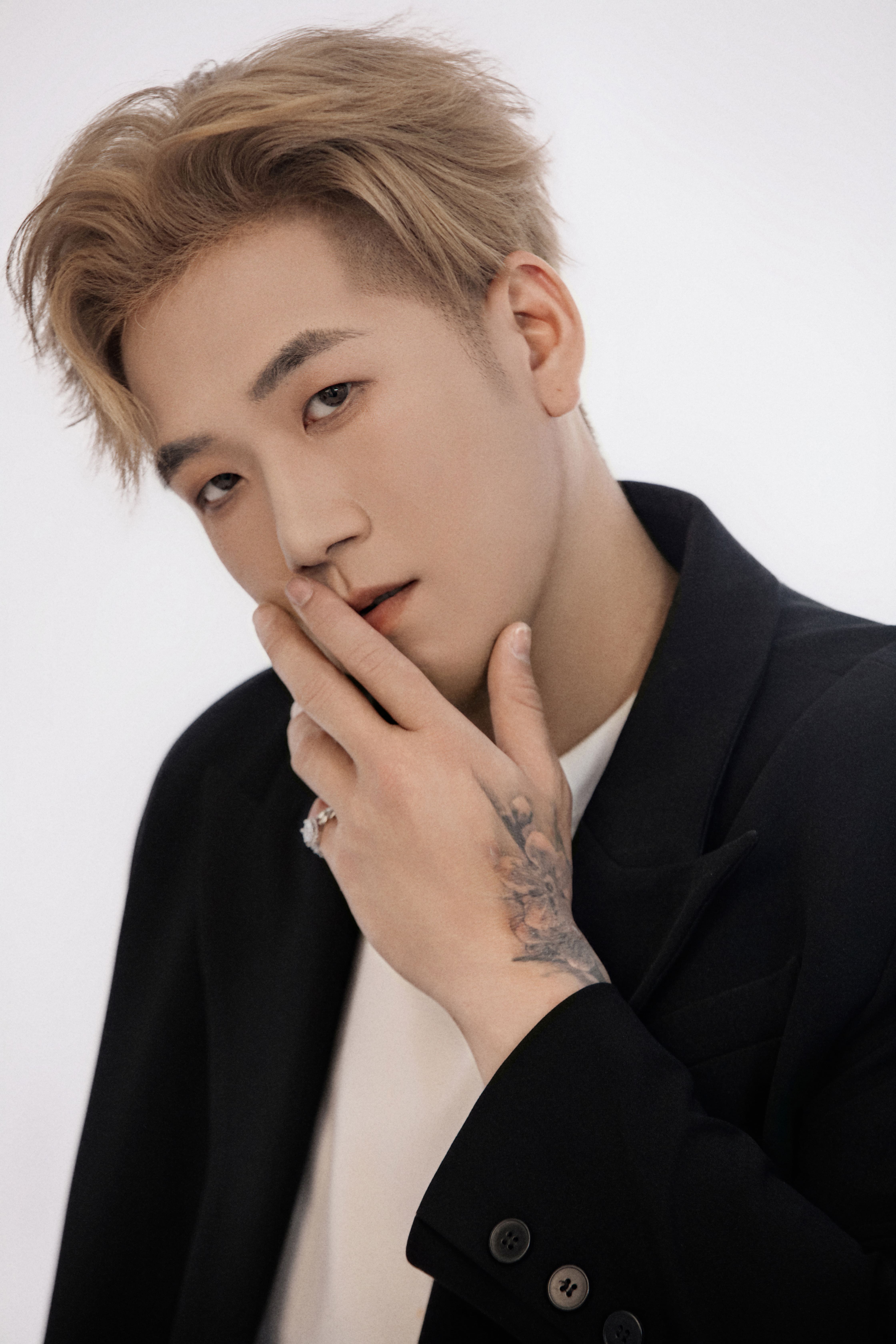 A man looks directly at the camera with his hand resting on his face.