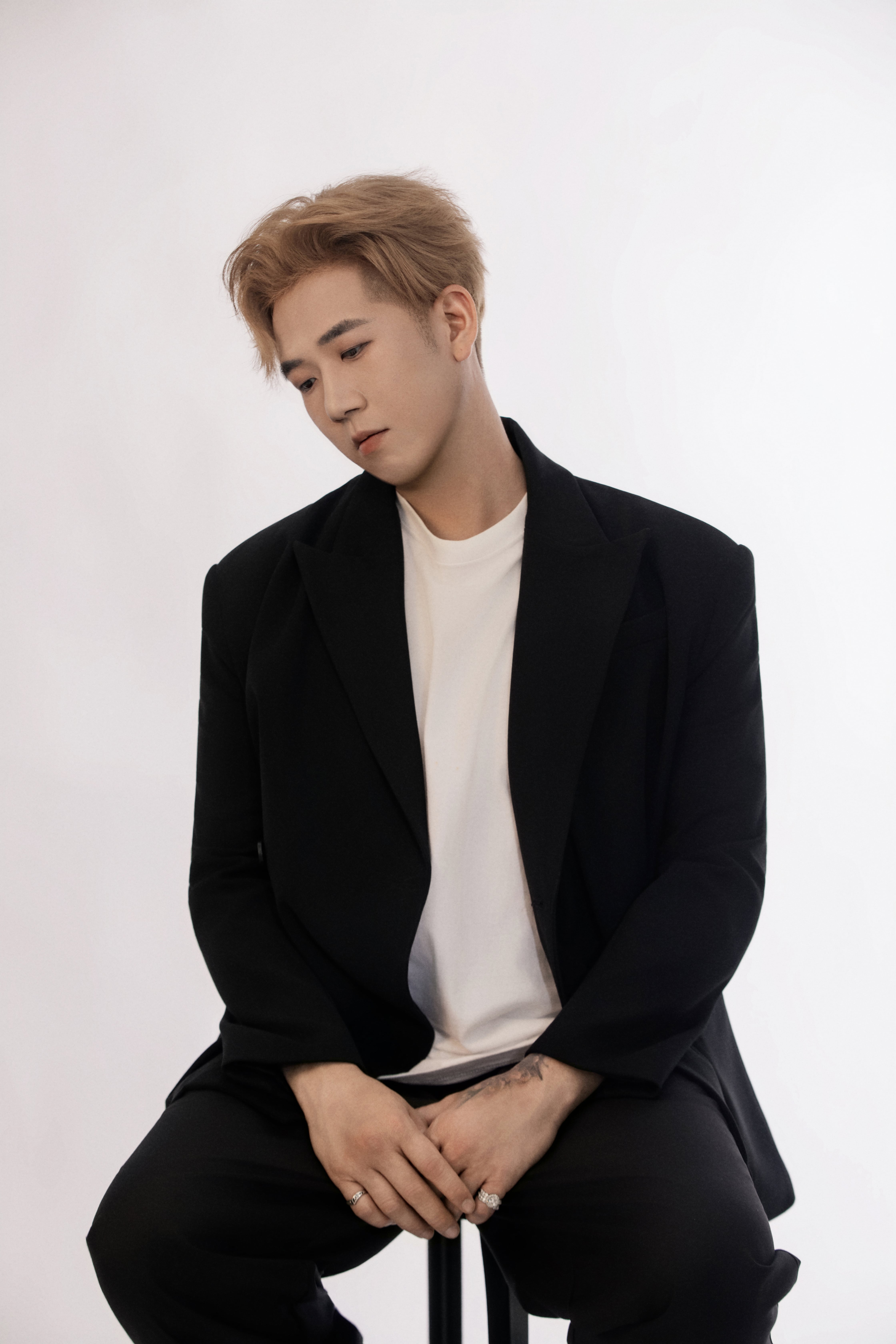 A man seated on a bar stool looks off toward the left