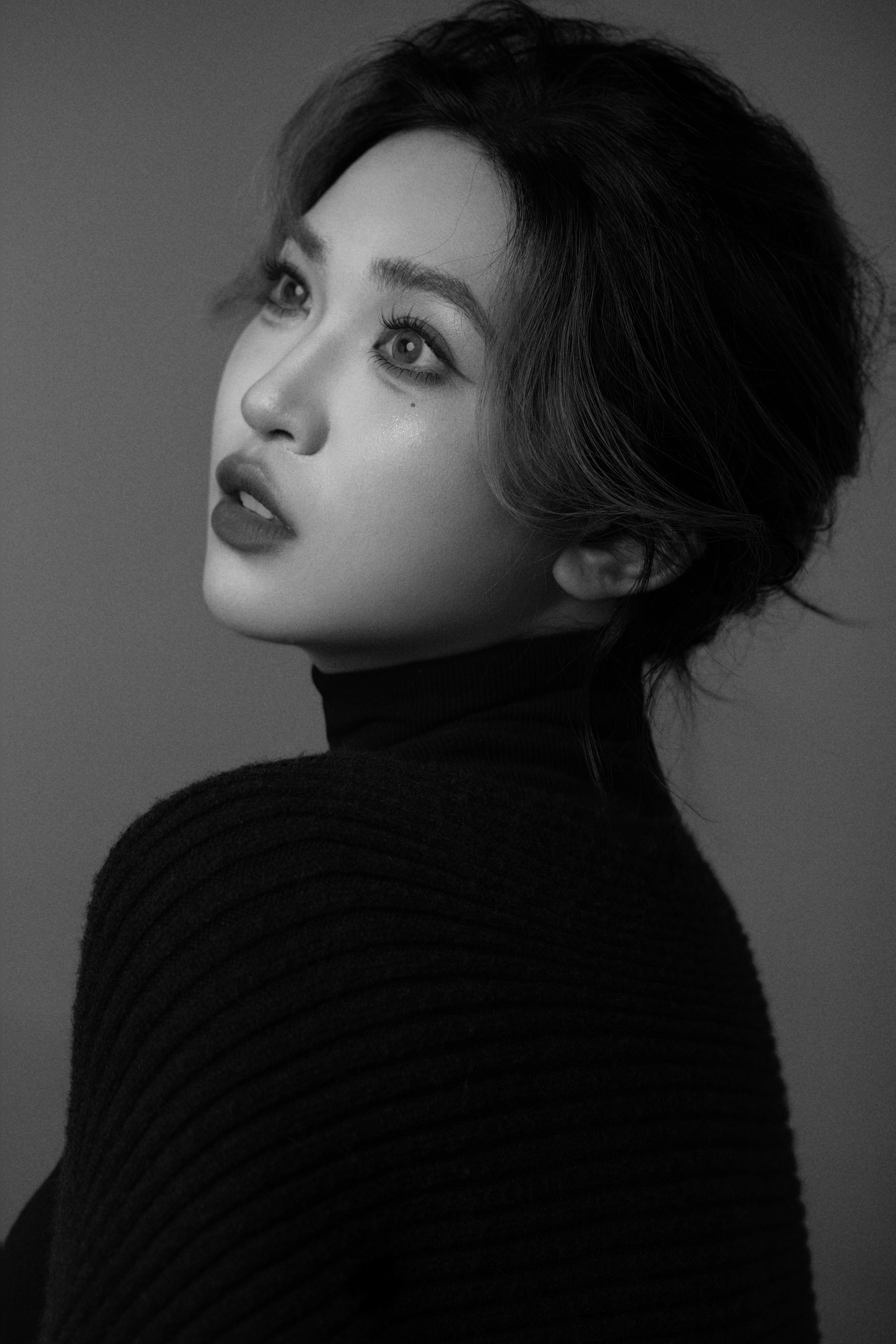 A black-and-white close-up of a woman gazing toward the left side.