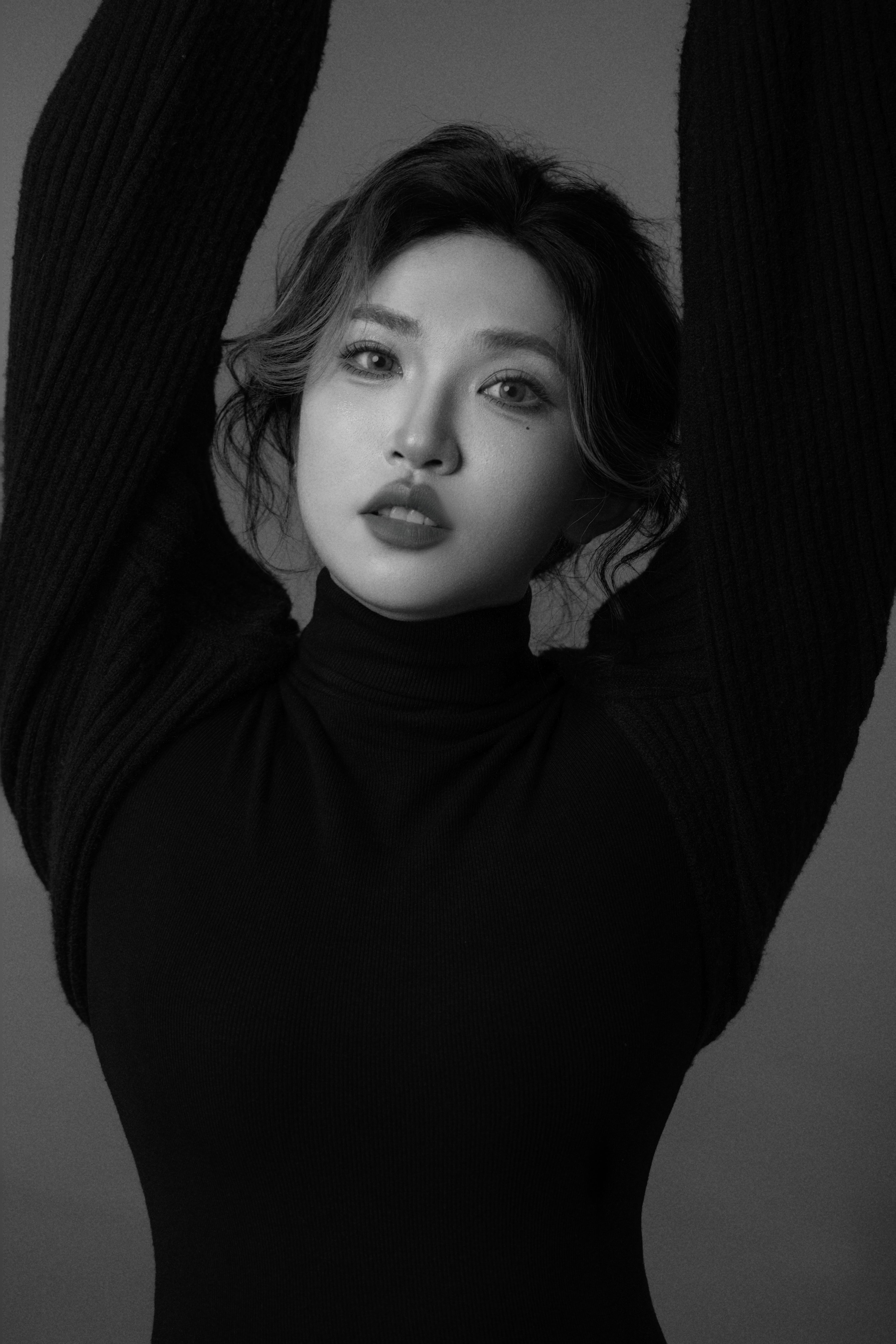 Silhouette of a woman with both arms raised, looking toward the camera in black and white.