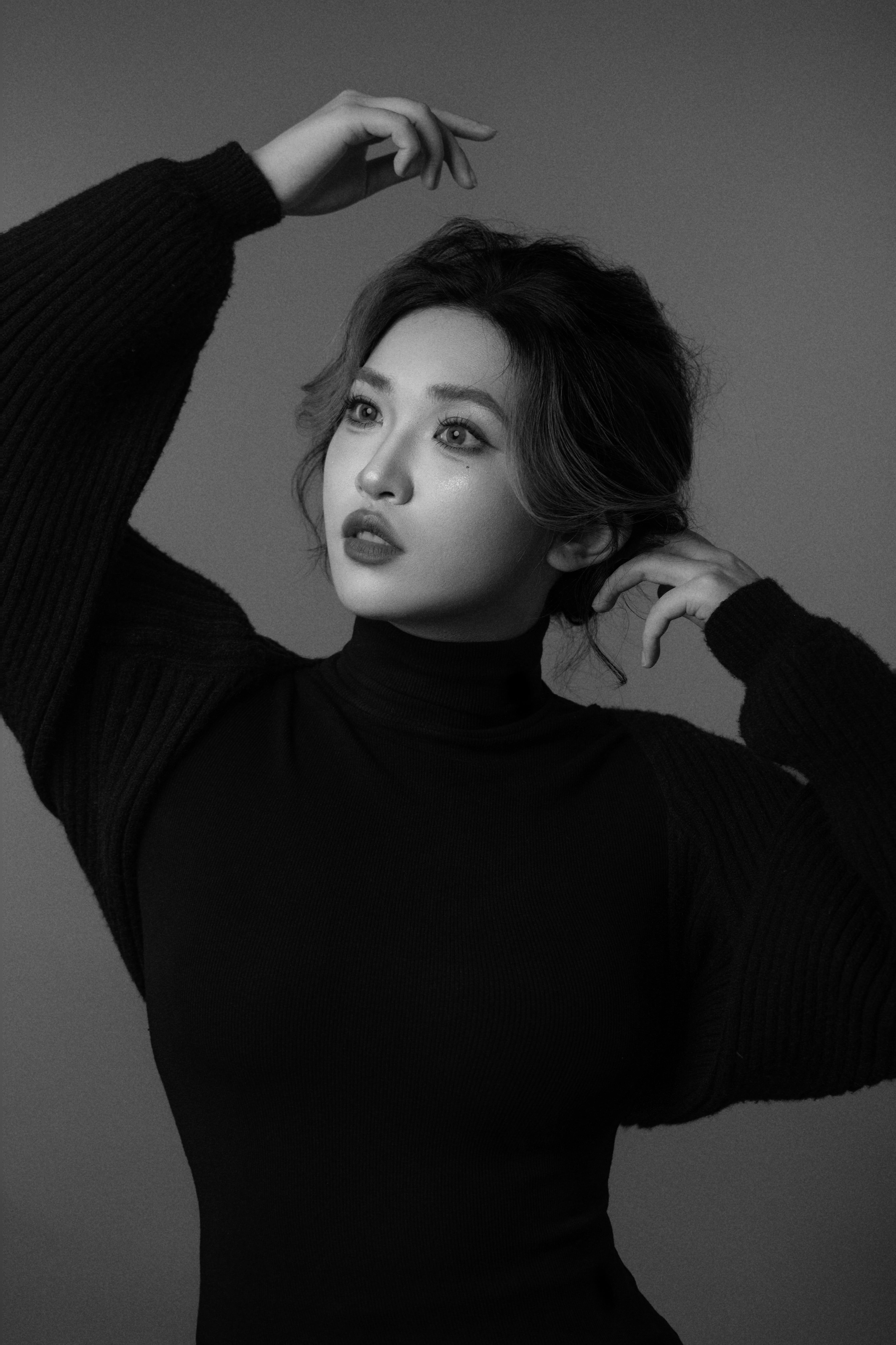 A black-and-white silhouette of a woman, captured while playing with her hair.