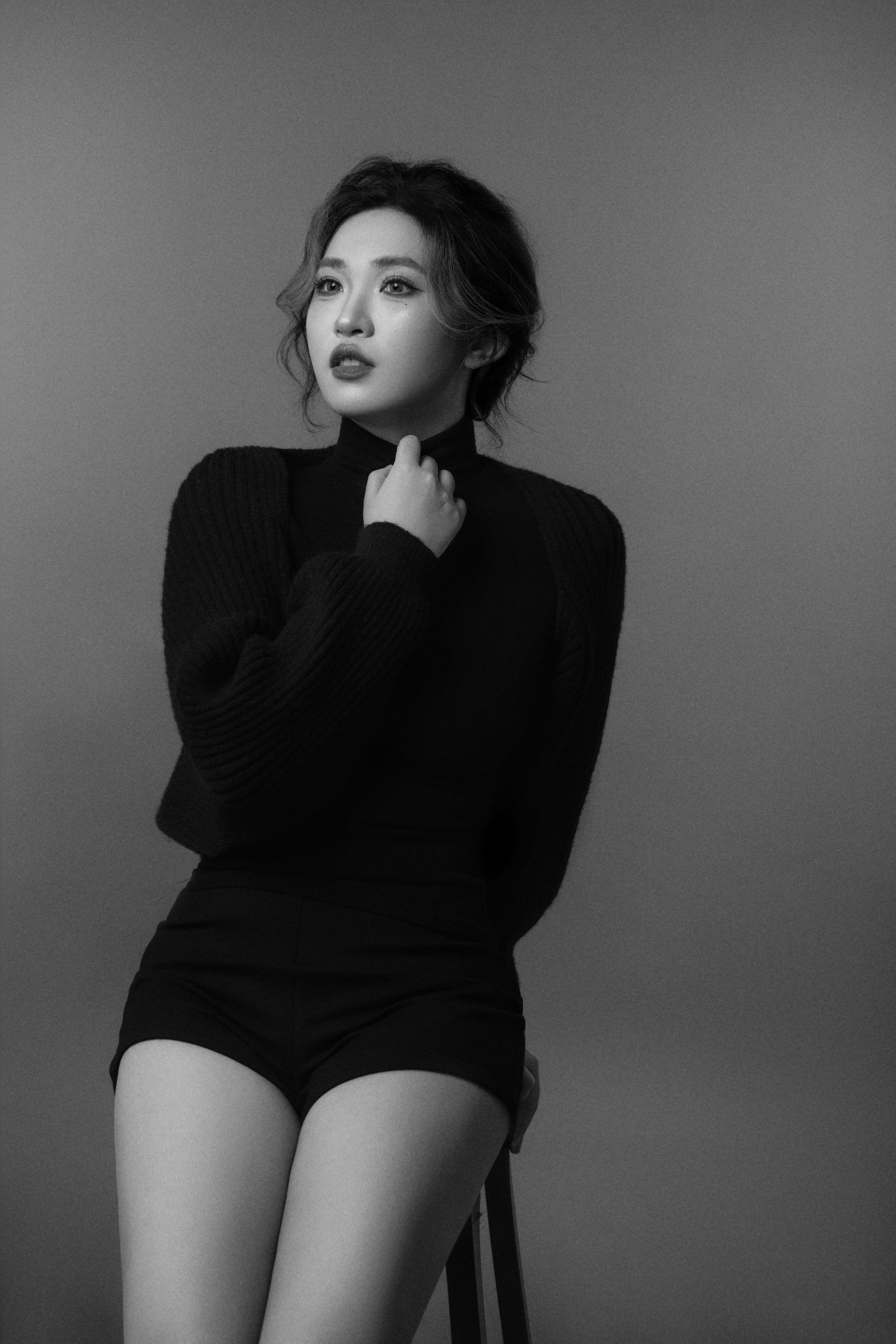 A black-and-white silhouette of a woman seated on a chair, one arm gently resting on her neck.