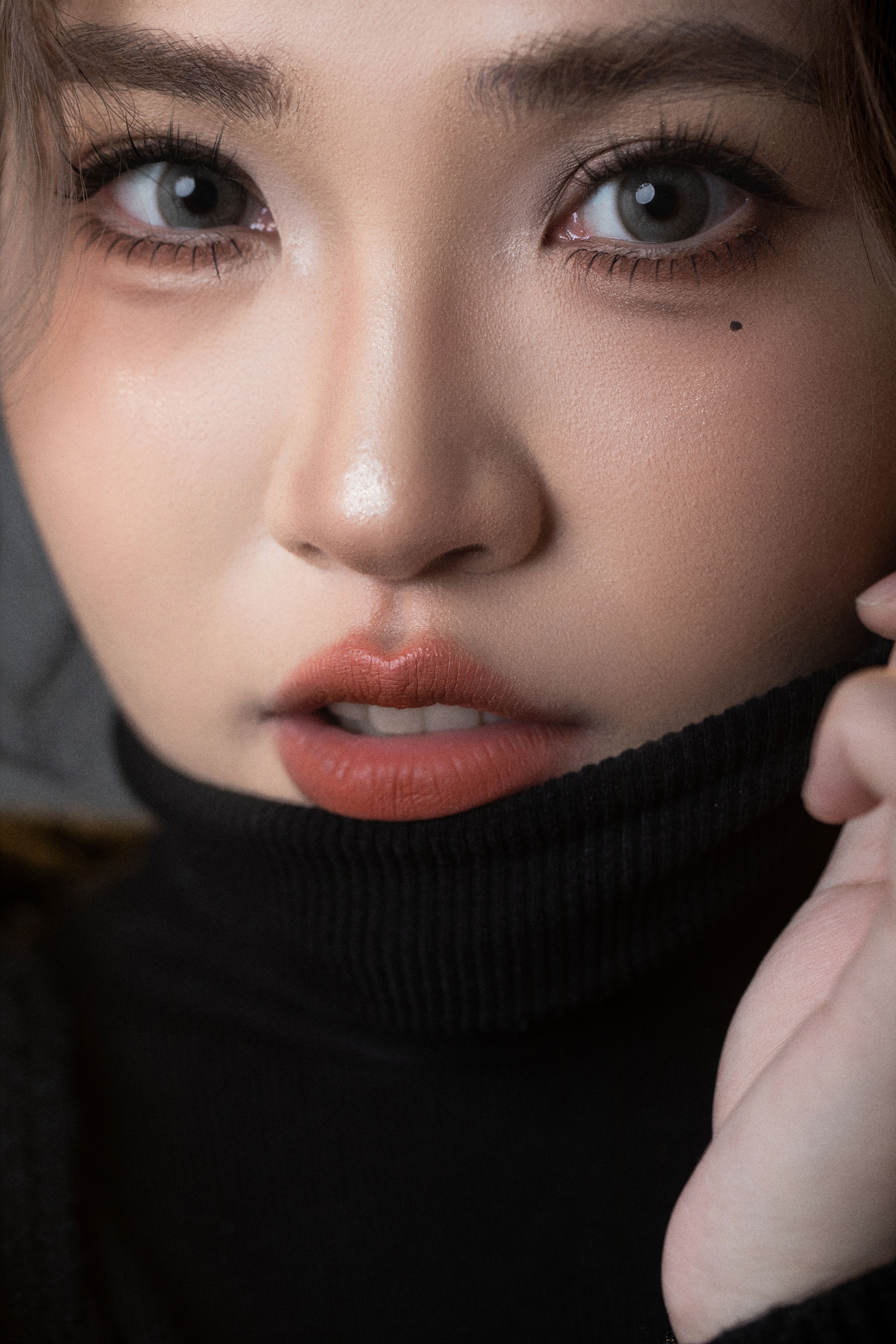 Extreme close-up of a woman looking at the camera while pulling up her shirt at the neck.