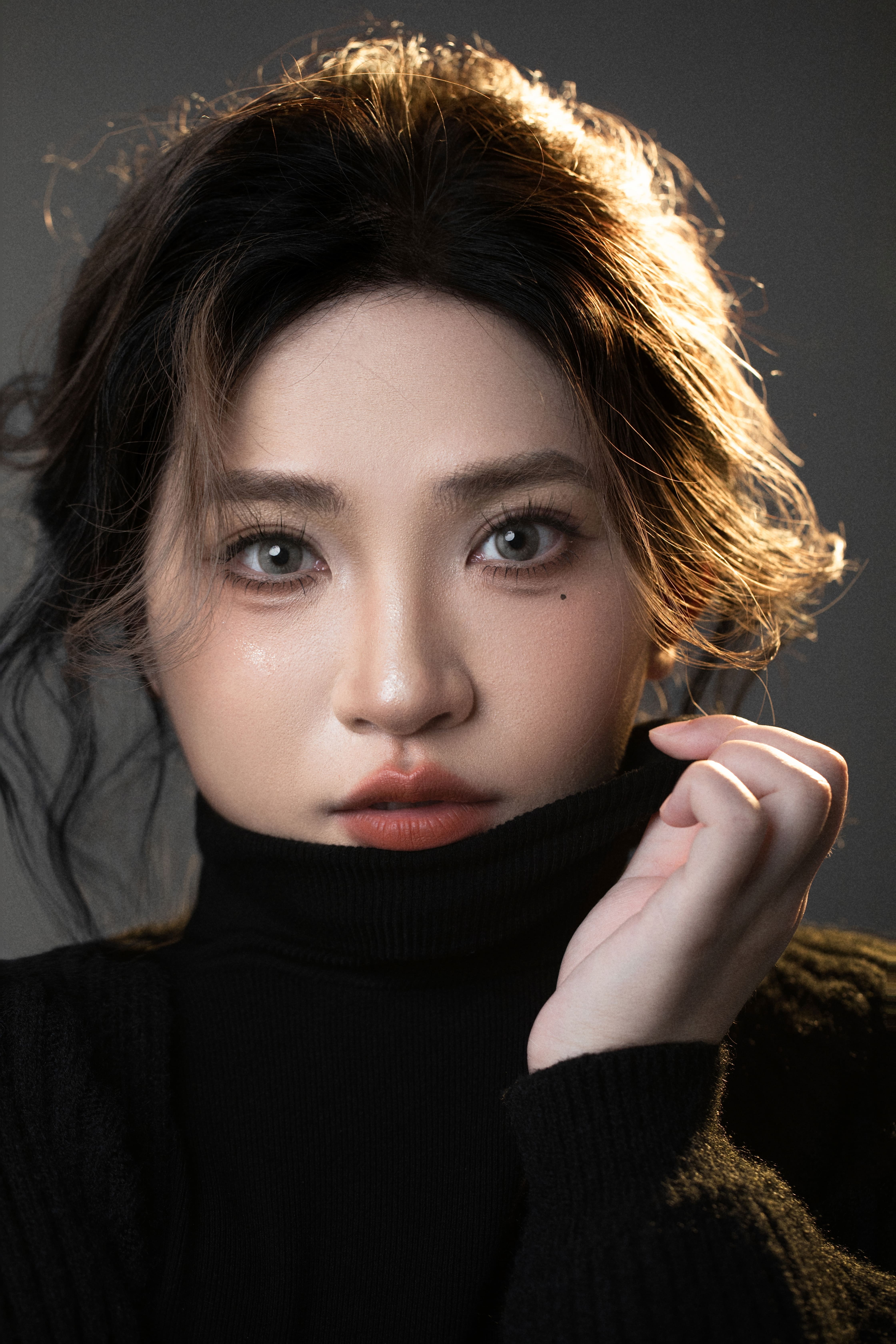 Close-up of a woman looking at the camera while pulling up her shirt at the neck.