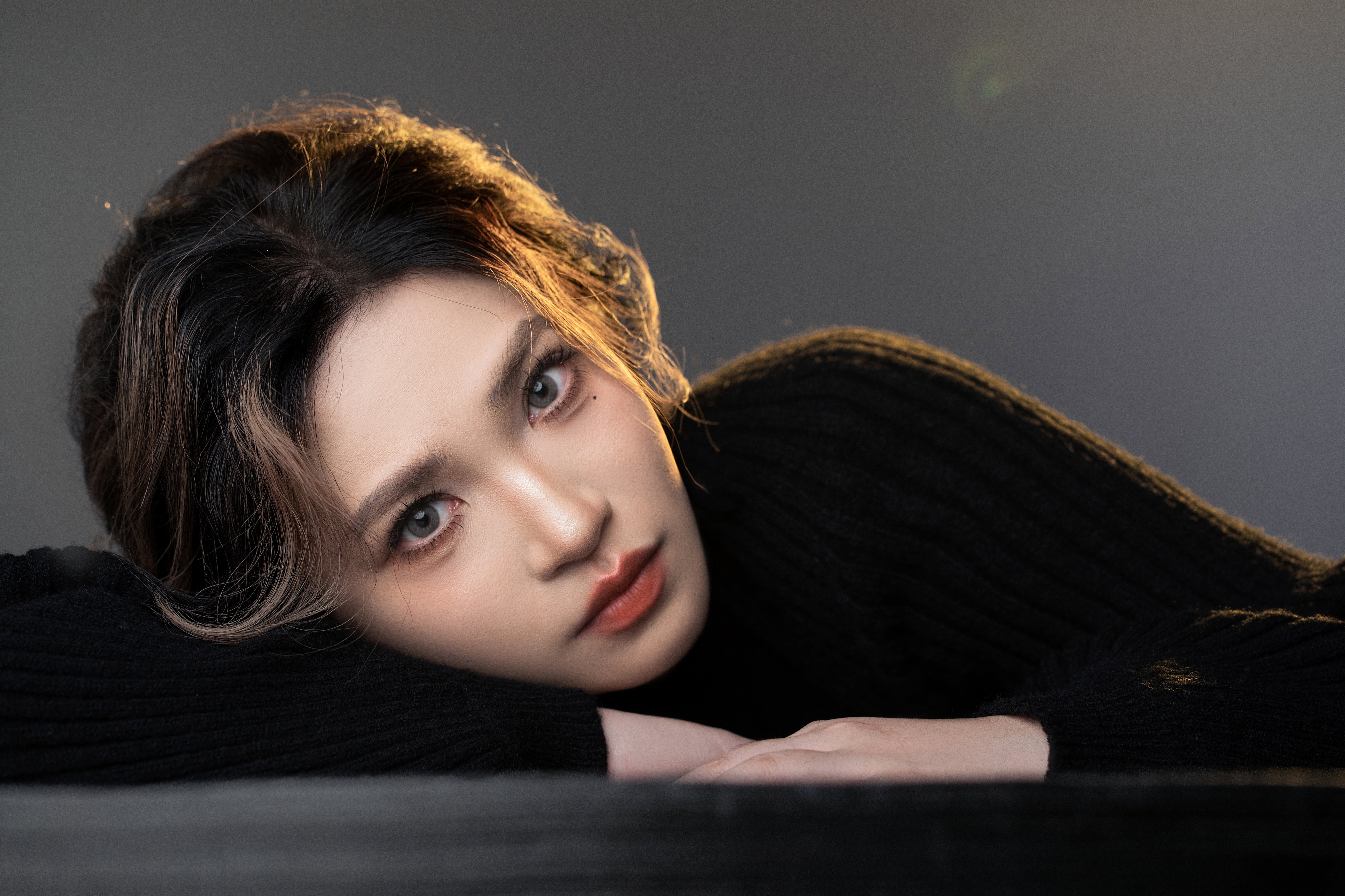 A woman lies on her side with her head resting on her arm, illuminated by golden light.