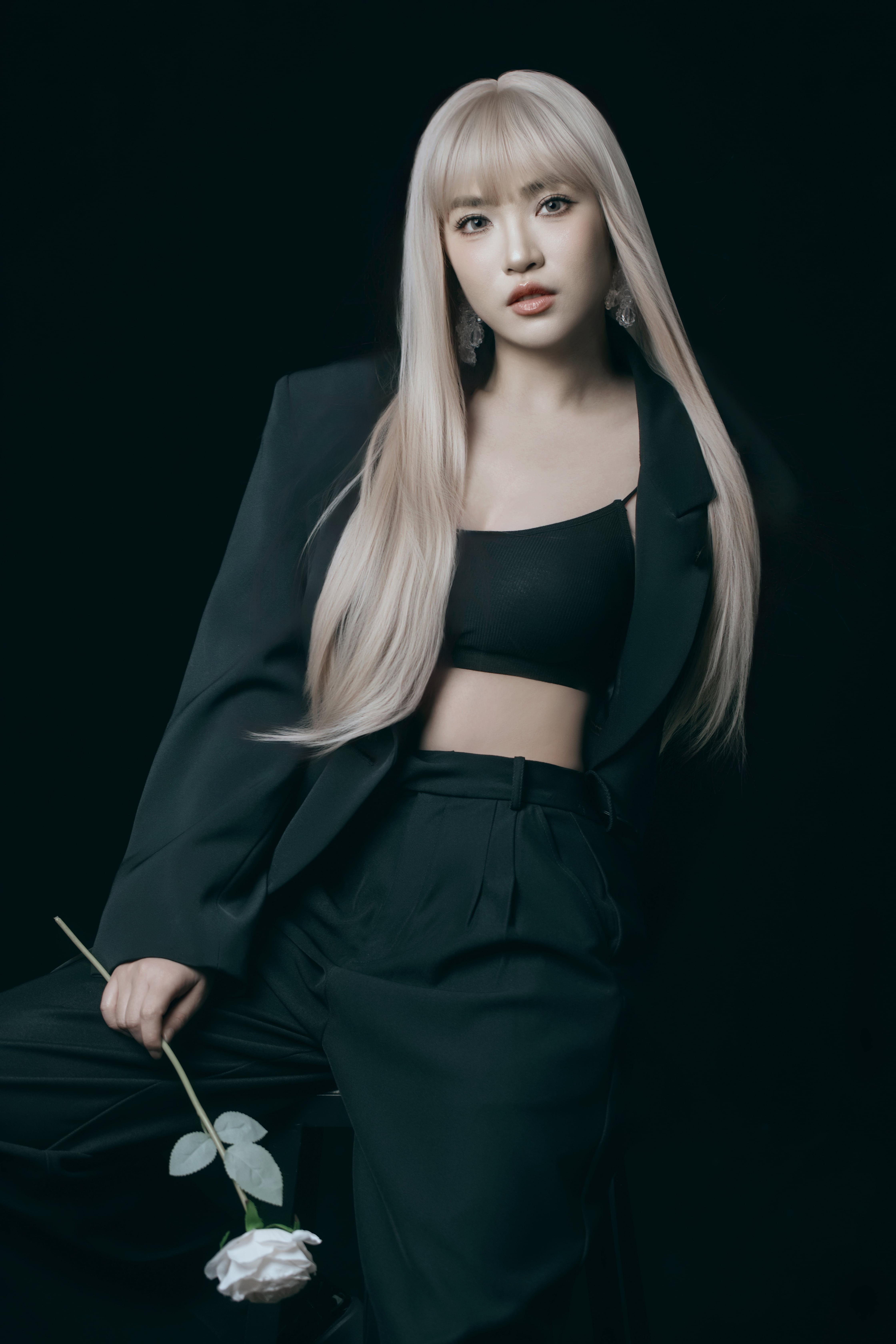 A woman rests back on a chair, gently holding a flower in one arm.