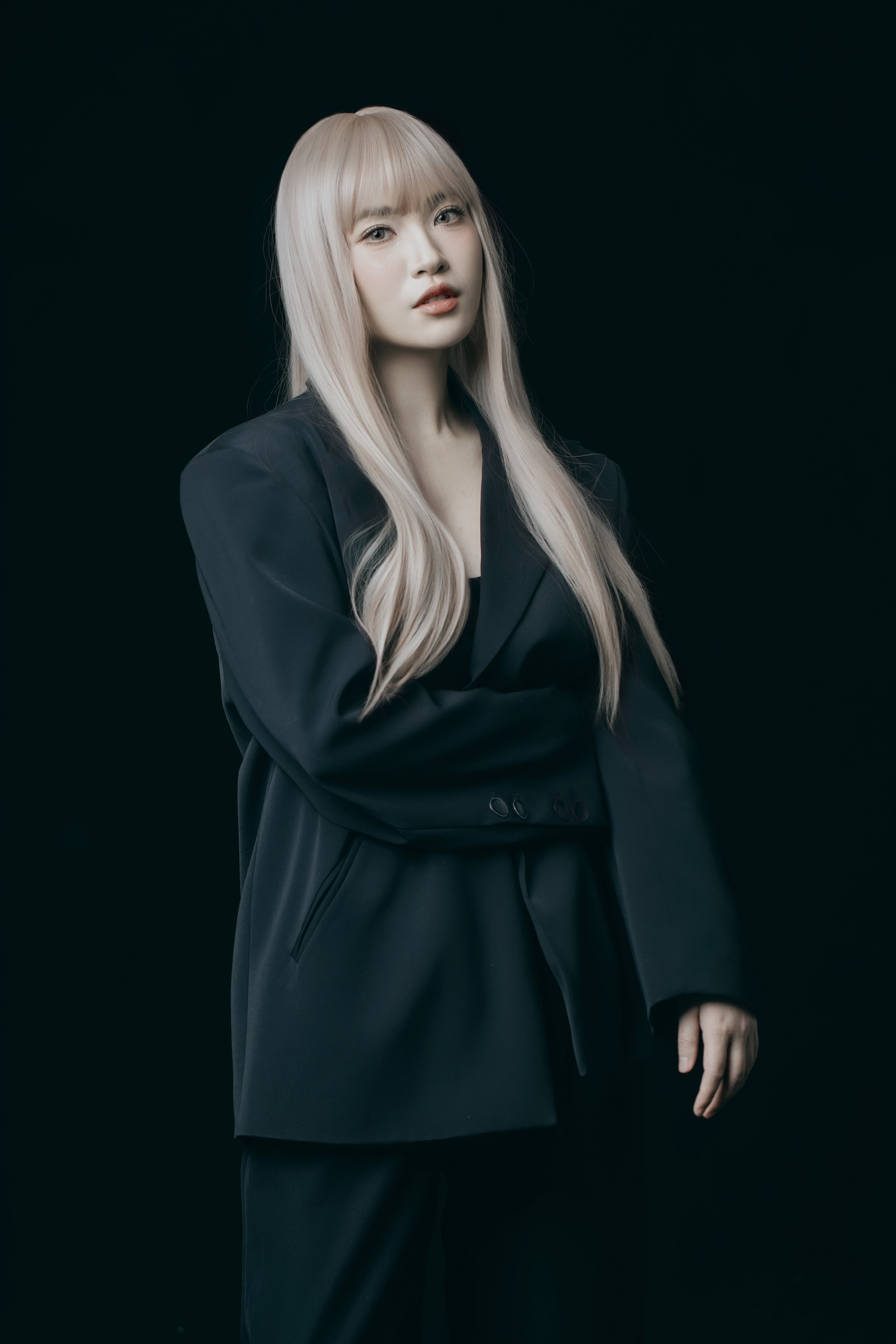 A woman stands posing, one arm resting around her waist.