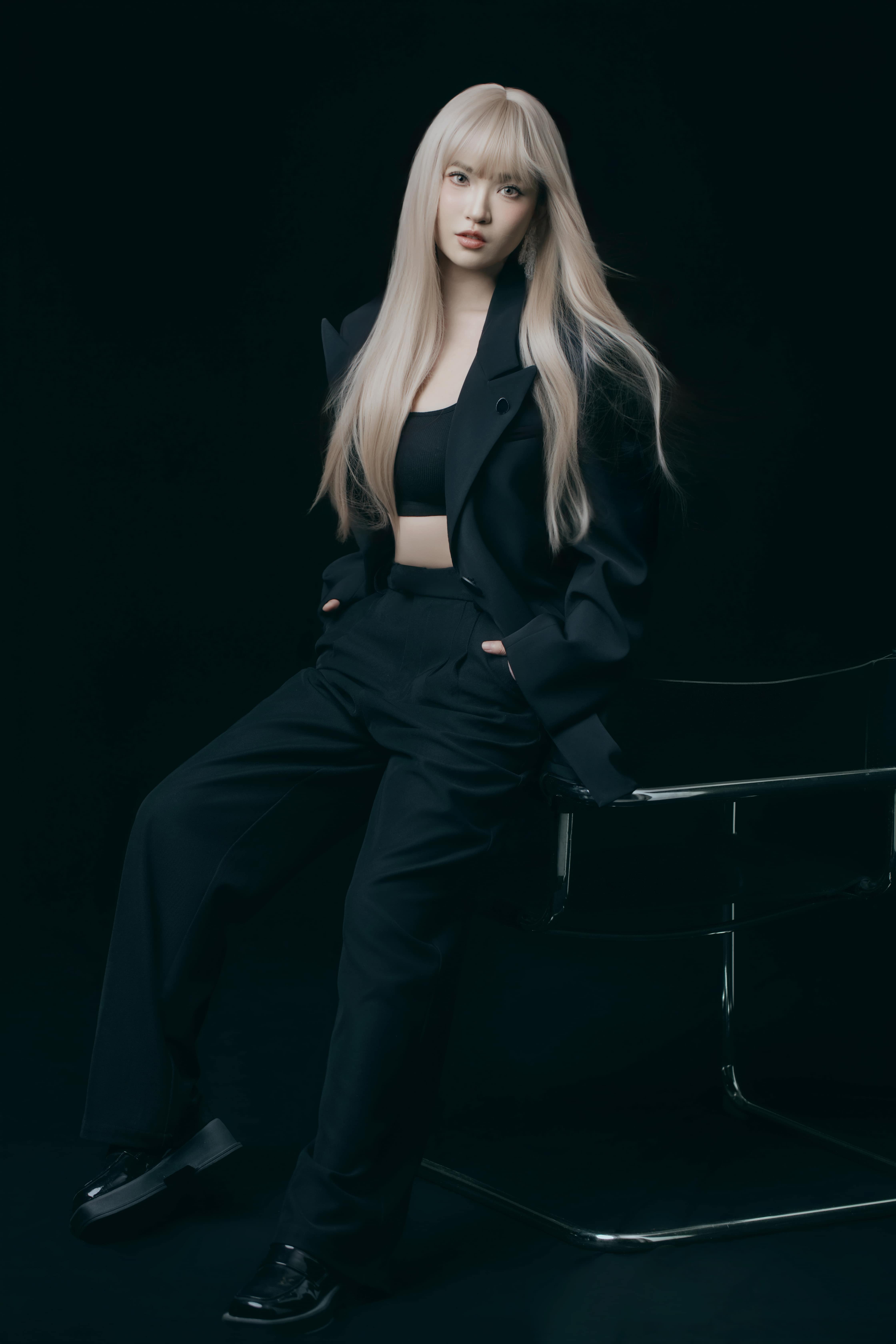 A woman rests on a chair with hands in pockets.