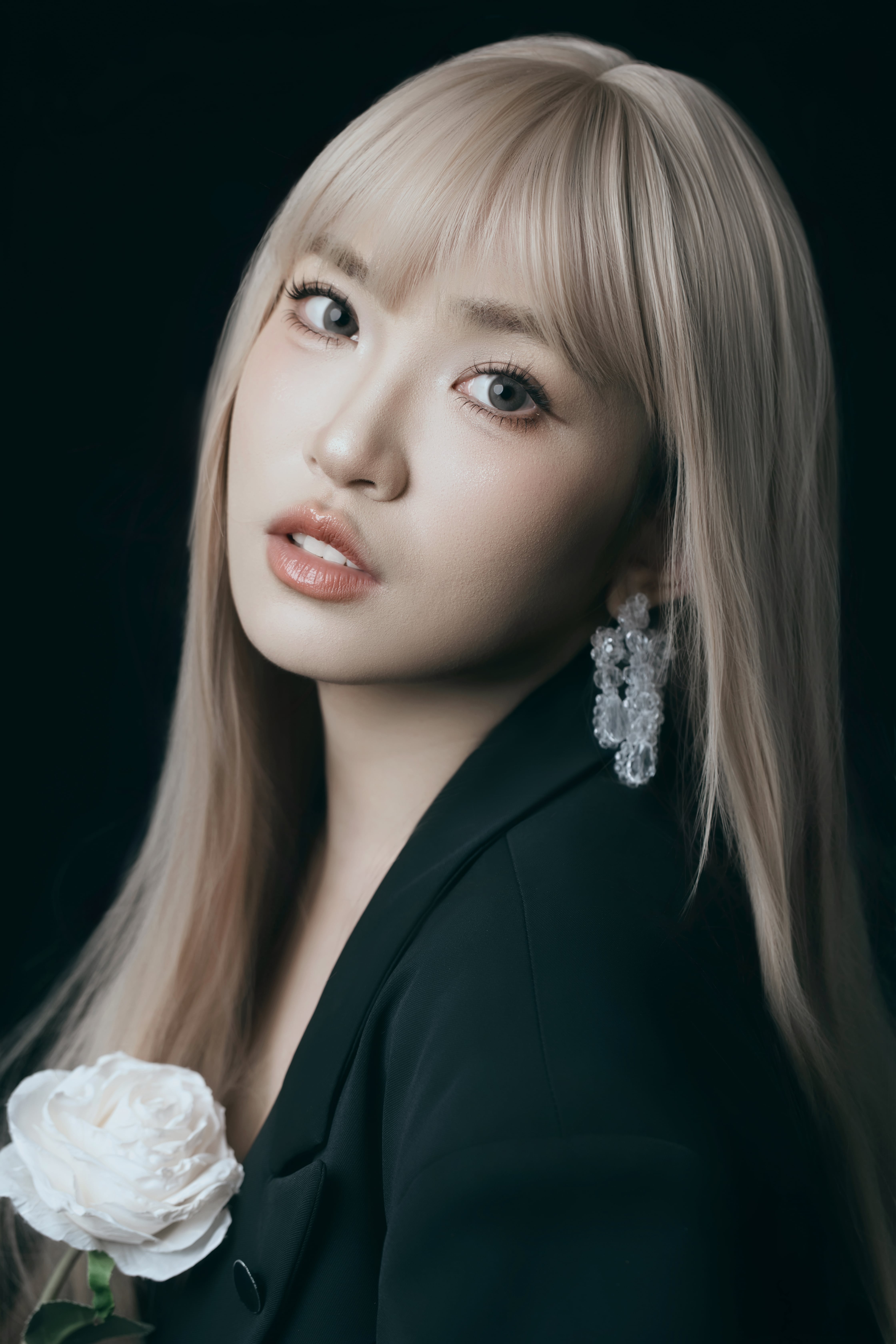 Close-up of a woman holding a flower and looking at the camera.