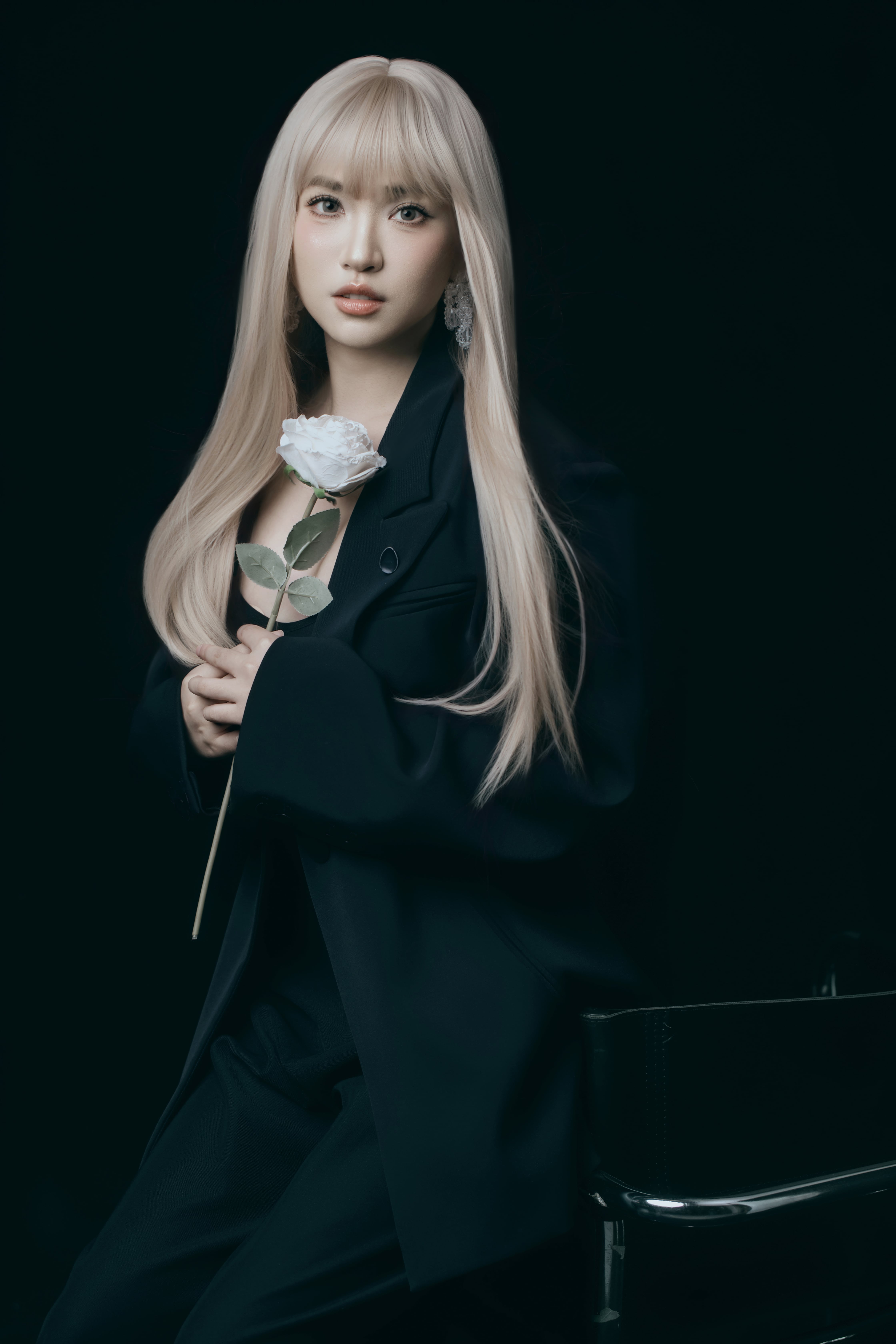 A woman rests on a chair holding a flower.