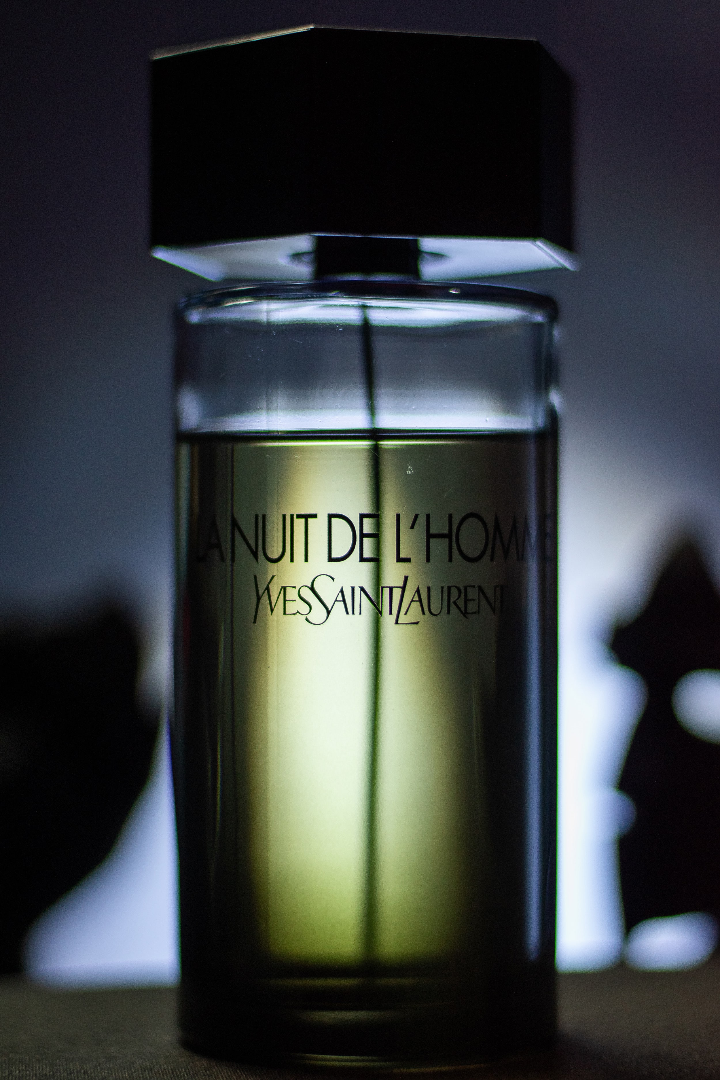 Dramatic film-style shot of La Nuit de L’Homme with white light highlighting the bottle’s details.