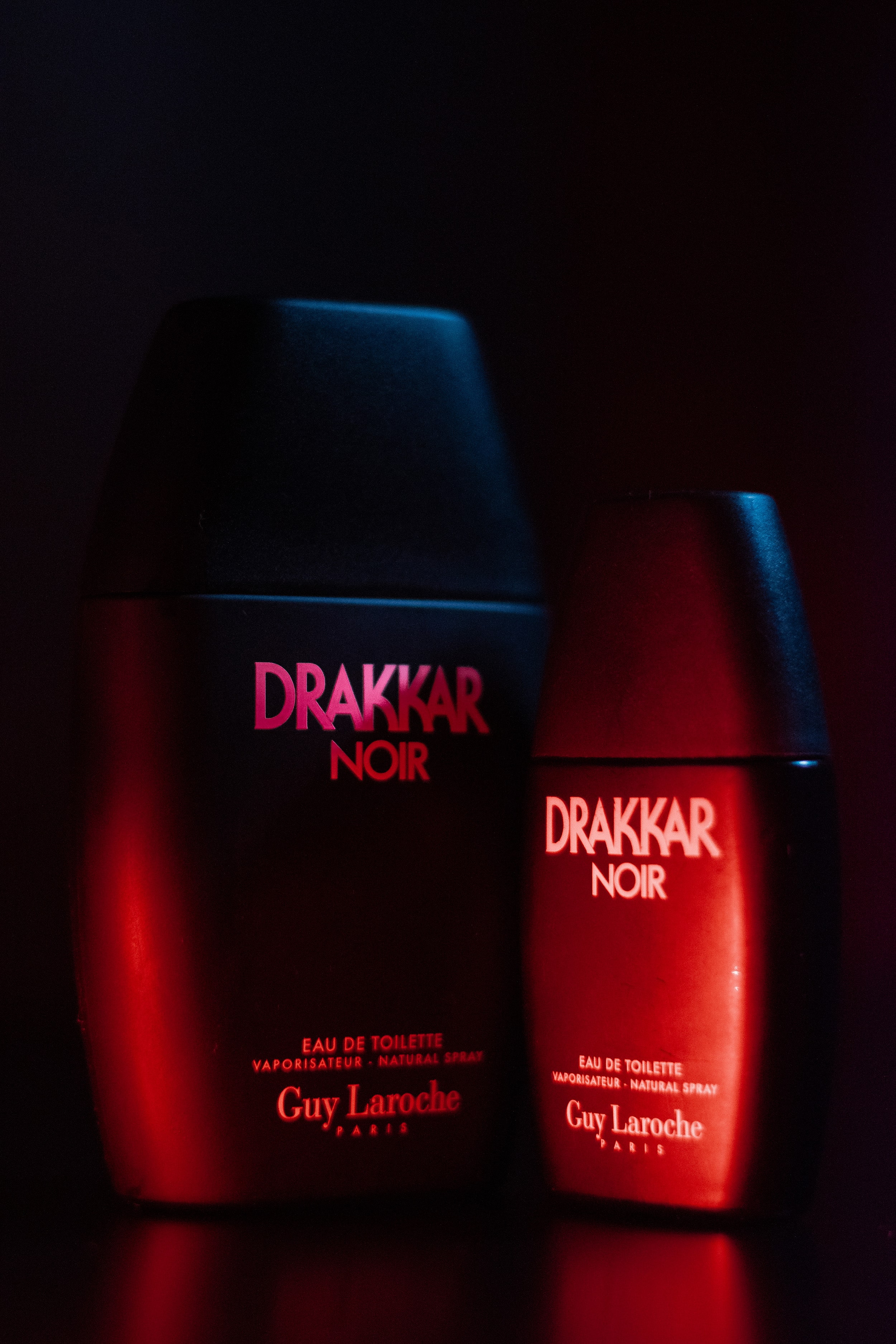 Drakker Cologne in a moody, cinematic setting, illuminated with soft red highlights and deep blue shadows for dramatic effect.