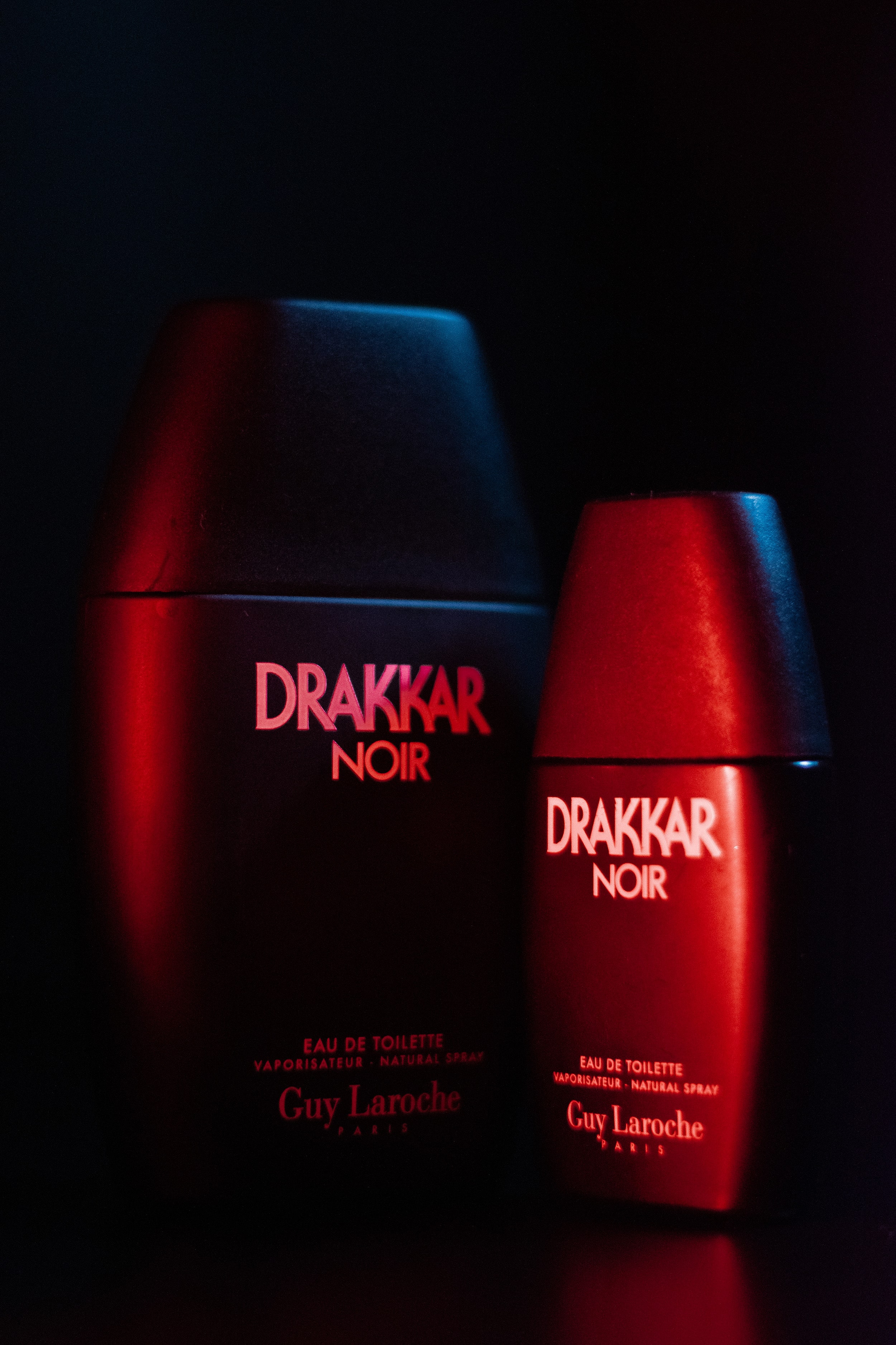 Close-up of Drakker Cologne in a film-inspired setup, contrasting blue and red lights enhancing its elegant design.