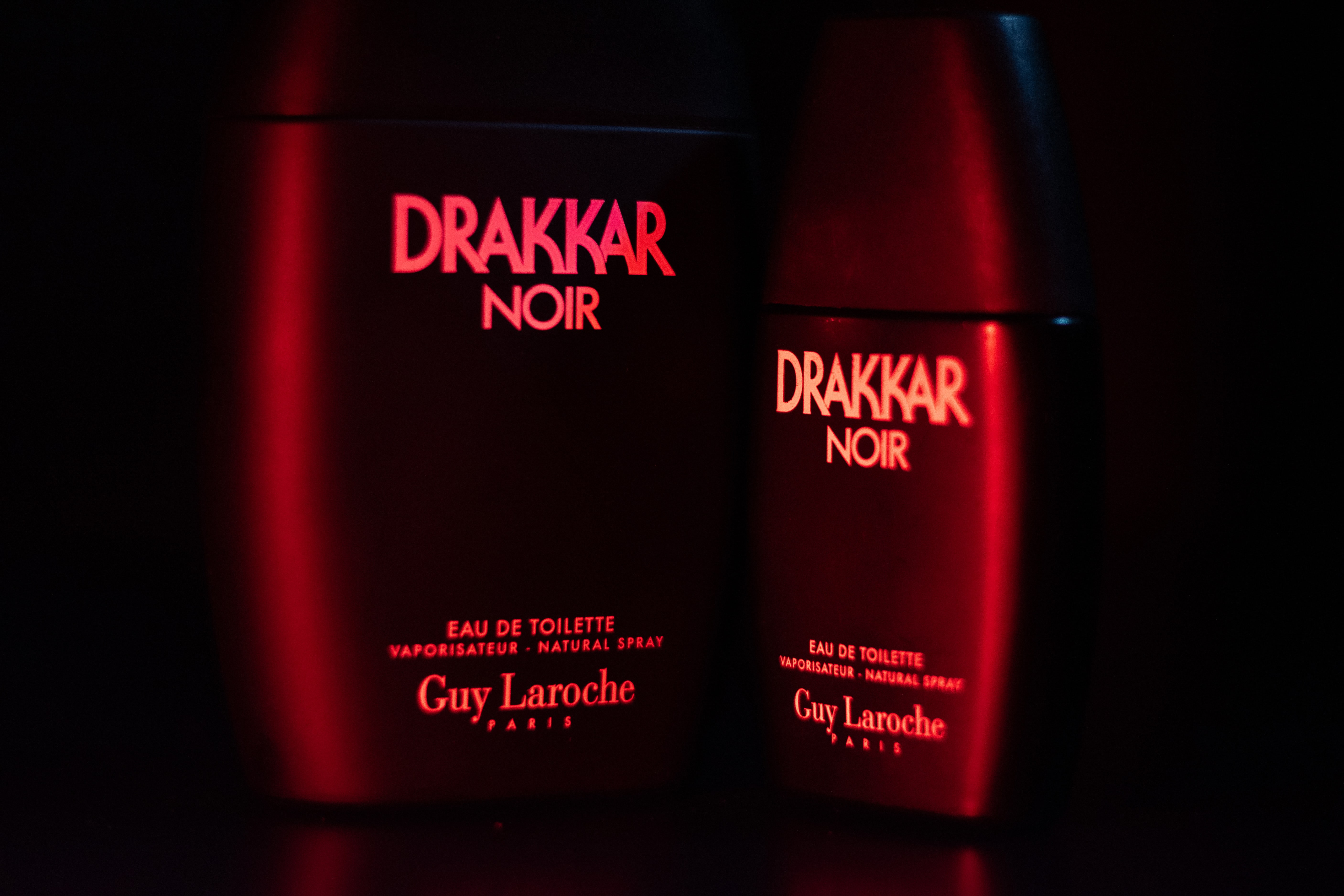 Drakker Cologne bottle lit with red lights in a cinematic environment.