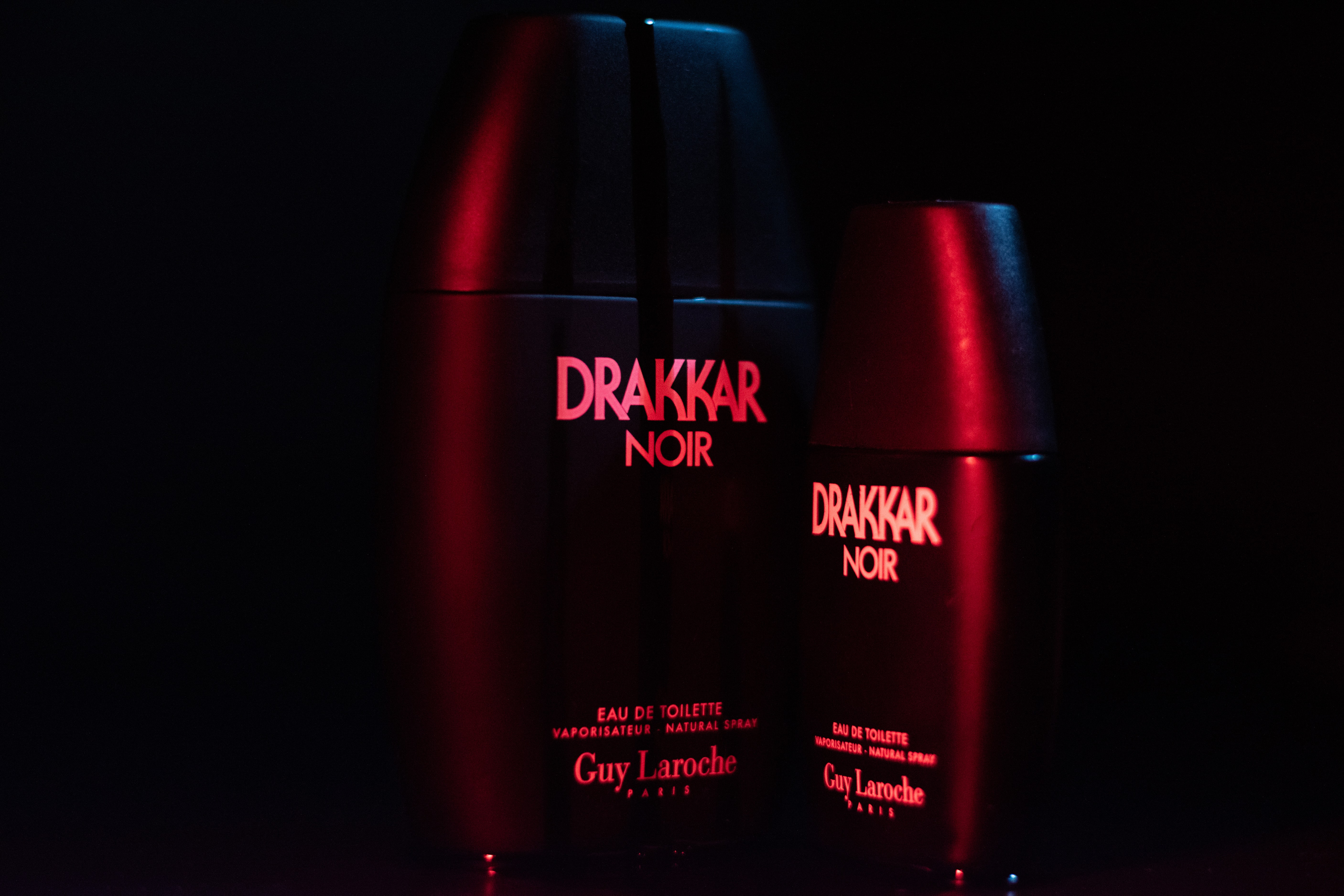 Drakker Cologne bottle in a cinematic setup, with contrasting blue and red lights adding depth and intensity.