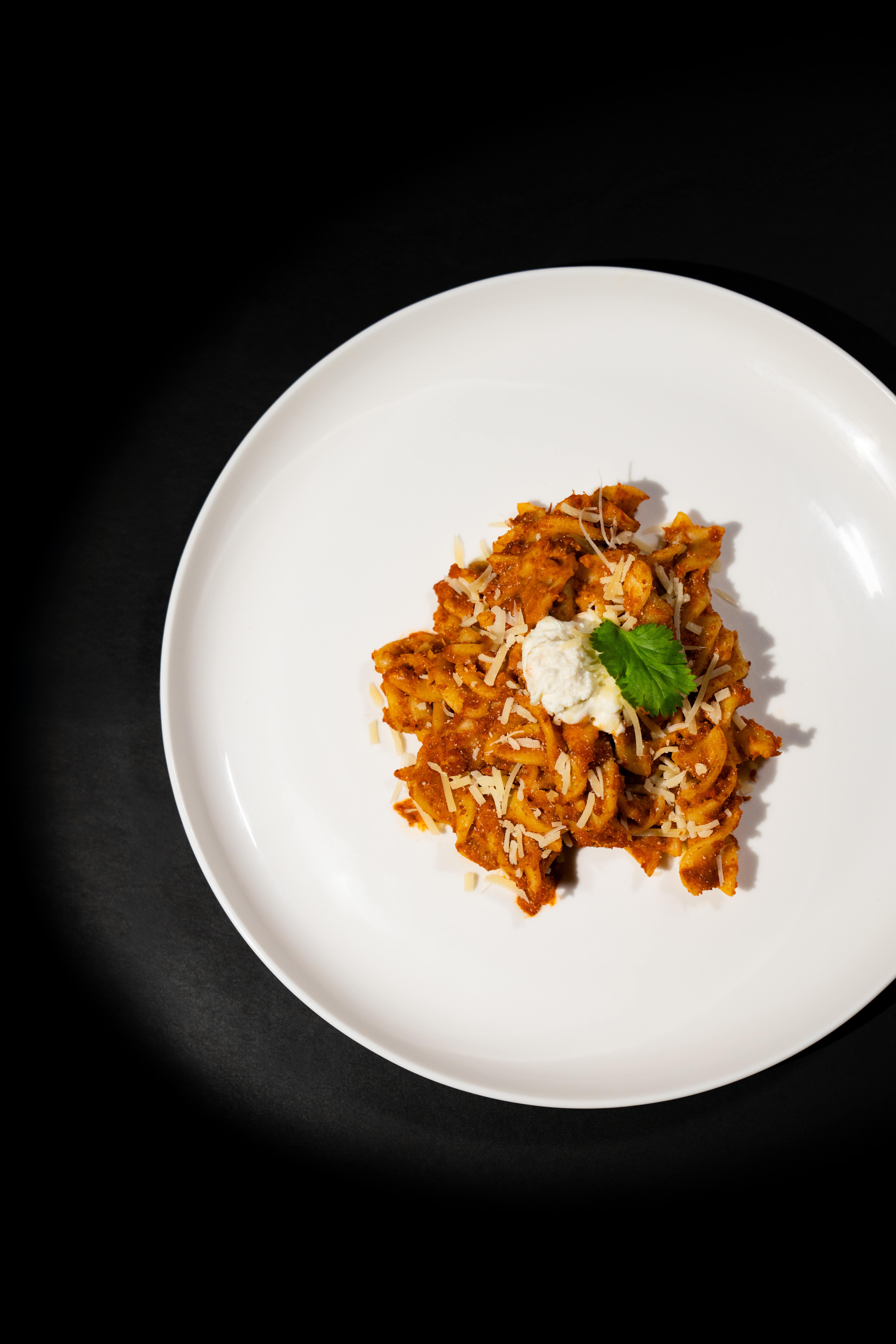 Top-down view of pasta on a white plate, photographed in a film-like setting with soft lighting.