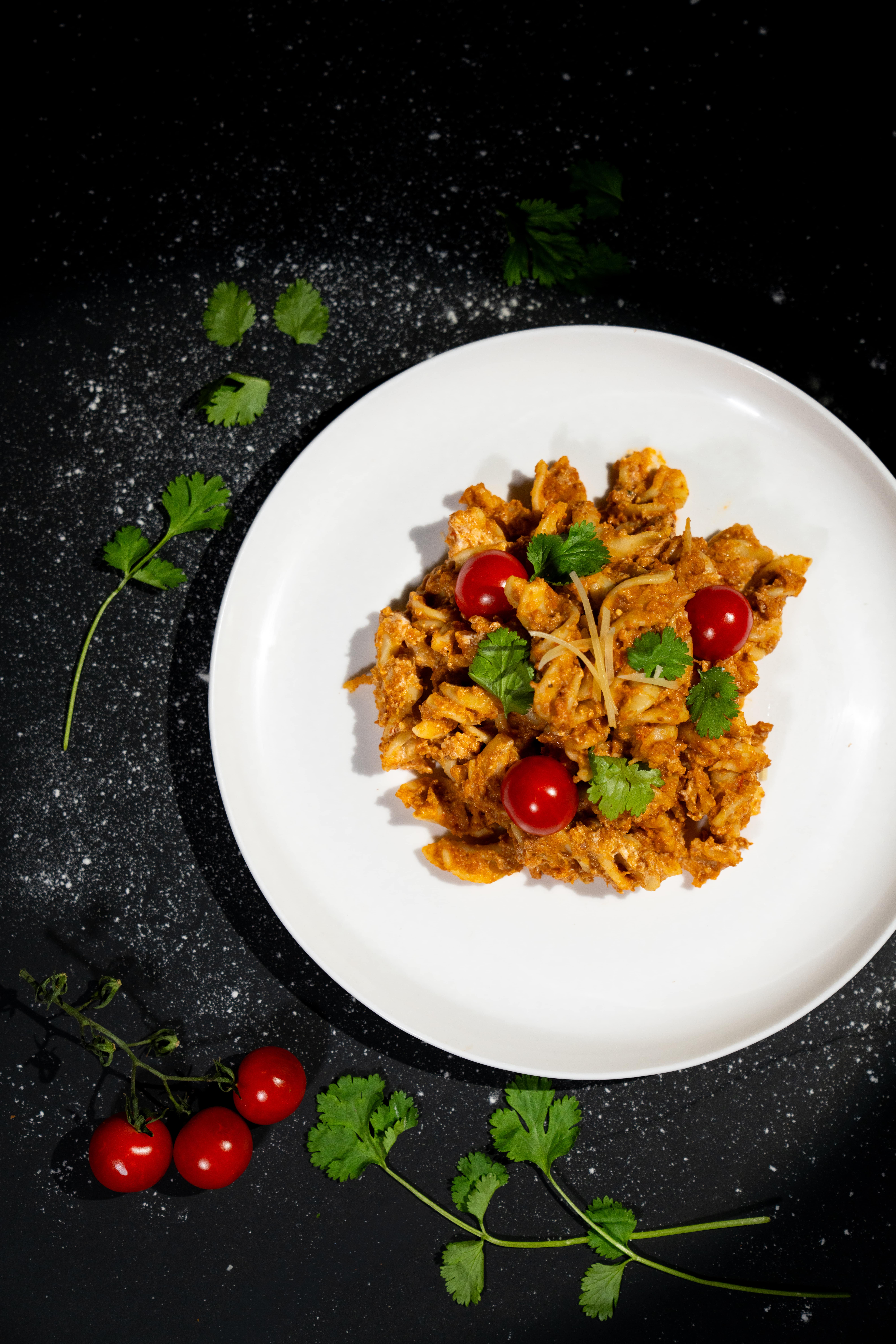 Overhead perspective of pasta on a white plate in a film-like scene, with gentle, cinematic lighting.