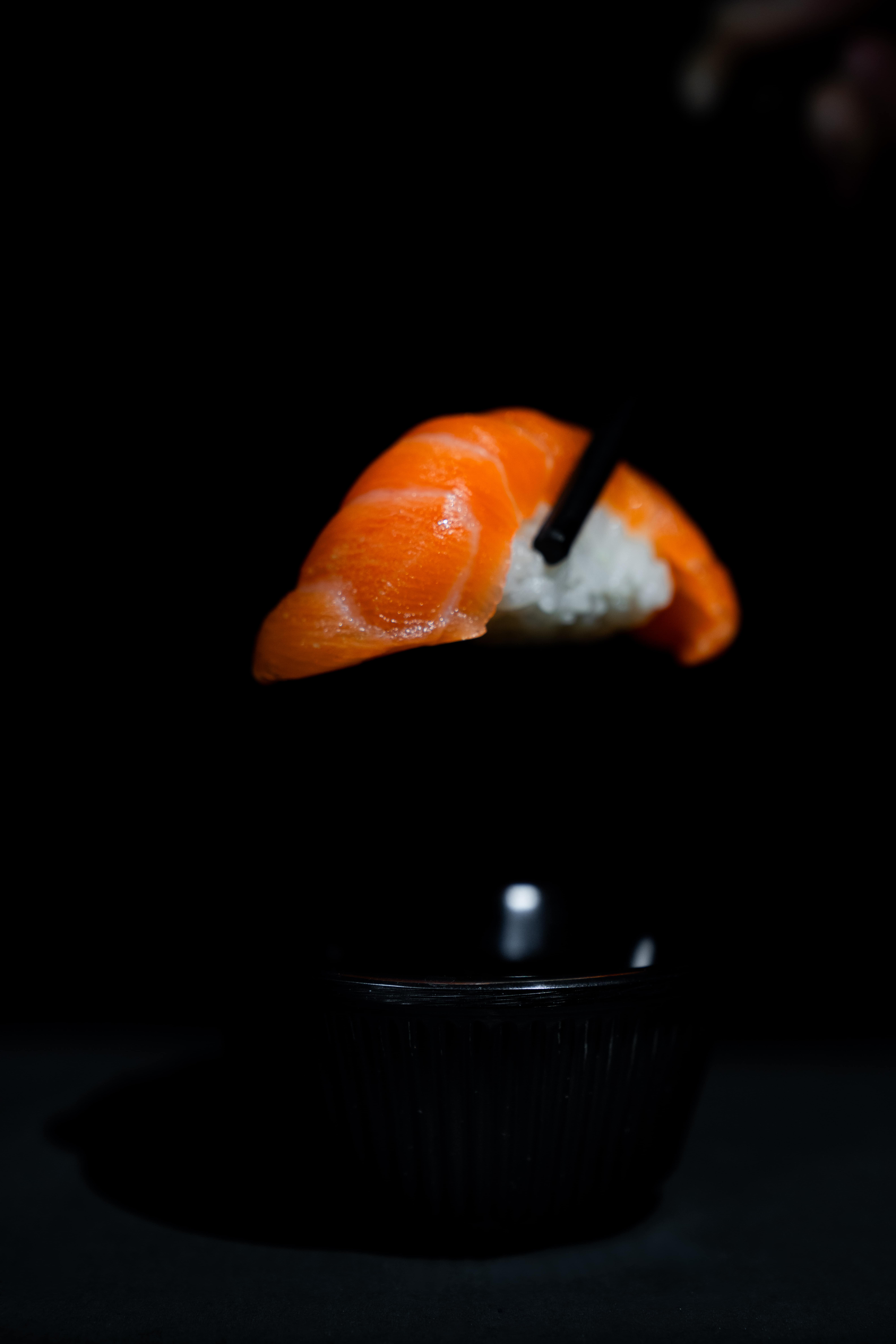 A cinematic close-up of sushi with gentle highlights and shadowed surroundings.
