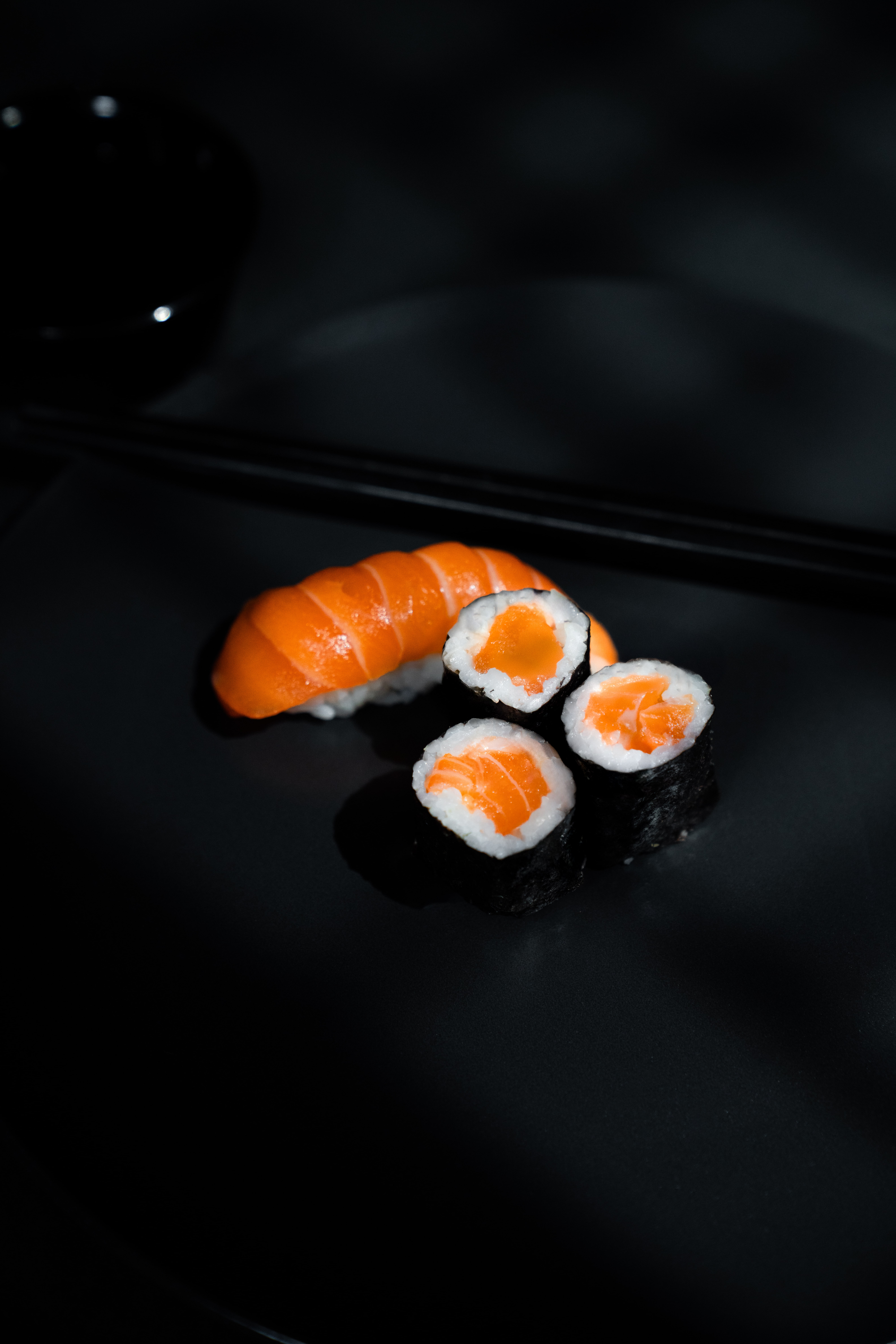 Sushi on a dark plate, lit softly to create a film-like, atmospheric mood.