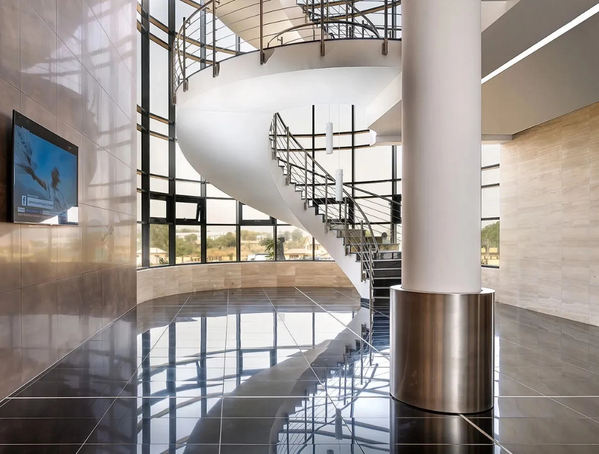 Modern interior with a white spiral staircase, large windows, and reflective black tiled floor.