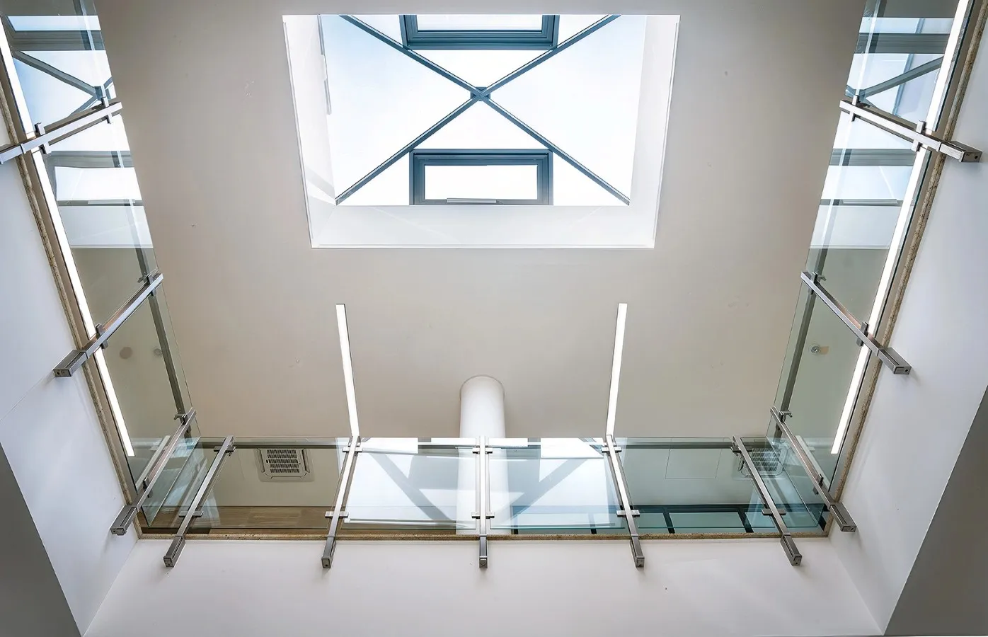 Interior view looking up at a skylight with glass railings on the surrounding balcony.