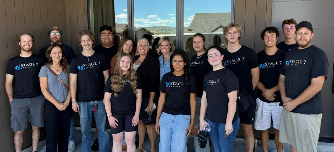 Group photo of the Stage 7 Design team, sixteen people standing outside a building, most wearing black 'Stage 7 Design' t-shirts.
