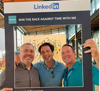 Two men standing next to each other in front of a picture frame.