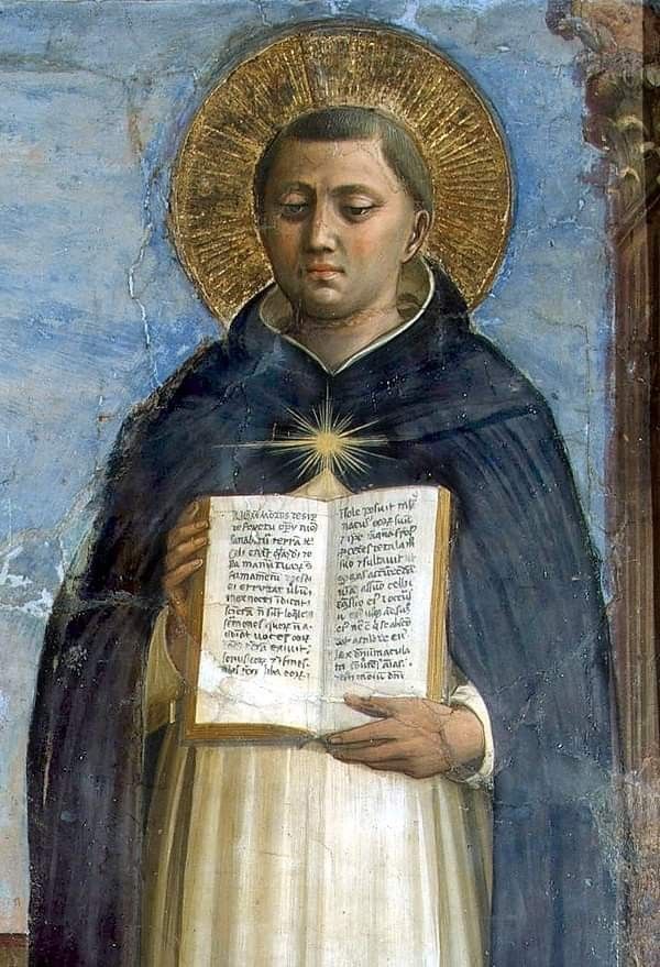 Santo Tomás de Aquino con aureola dorada sostiene un libro abierto con texto en latín.