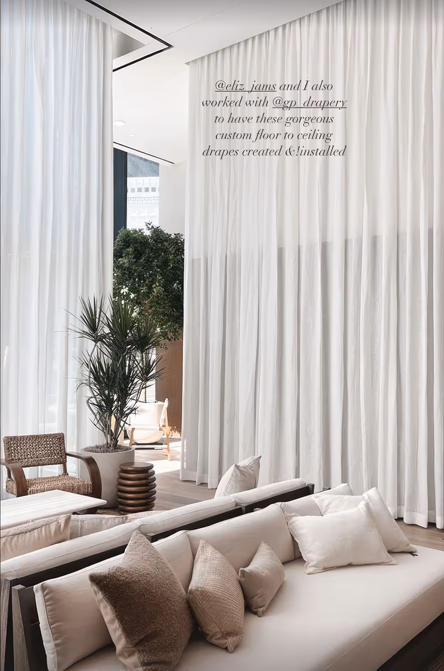 Luxury living room in Dallas, TX with floor-to-ceiling white drapes, elegant seating, and potted greenery.