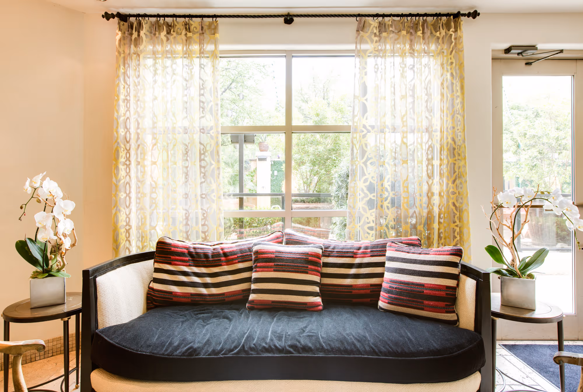 Stylish lobby seating area in Dallas, TX featuring vibrant striped cushions and decorative drapery.