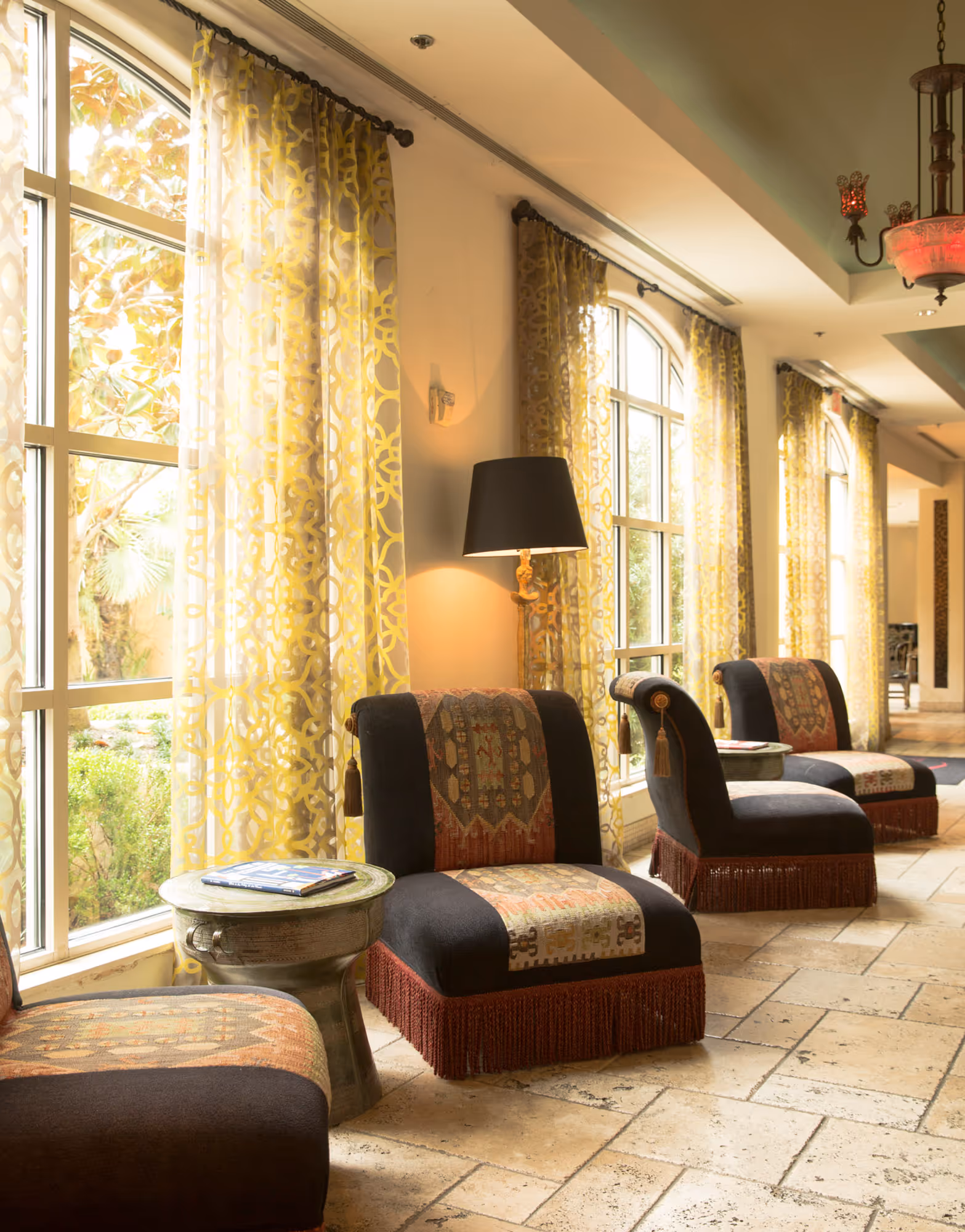 Luxury lobby seating with patterned chairs and sheer yellow drapes in a stylish hotel in Dallas, TX.