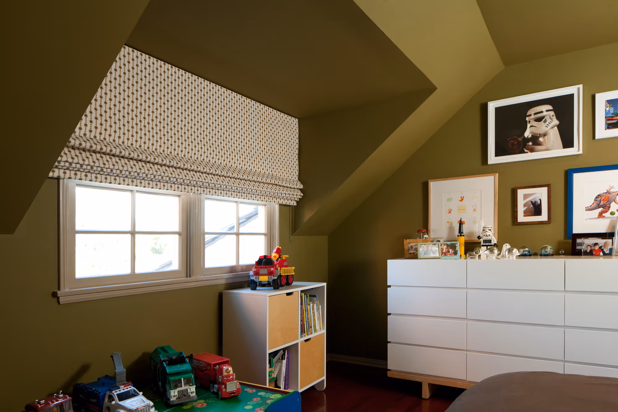 Stylish boys' bedroom featuring olive green walls, Roman shades, and playful decor in Hollywood, CA.