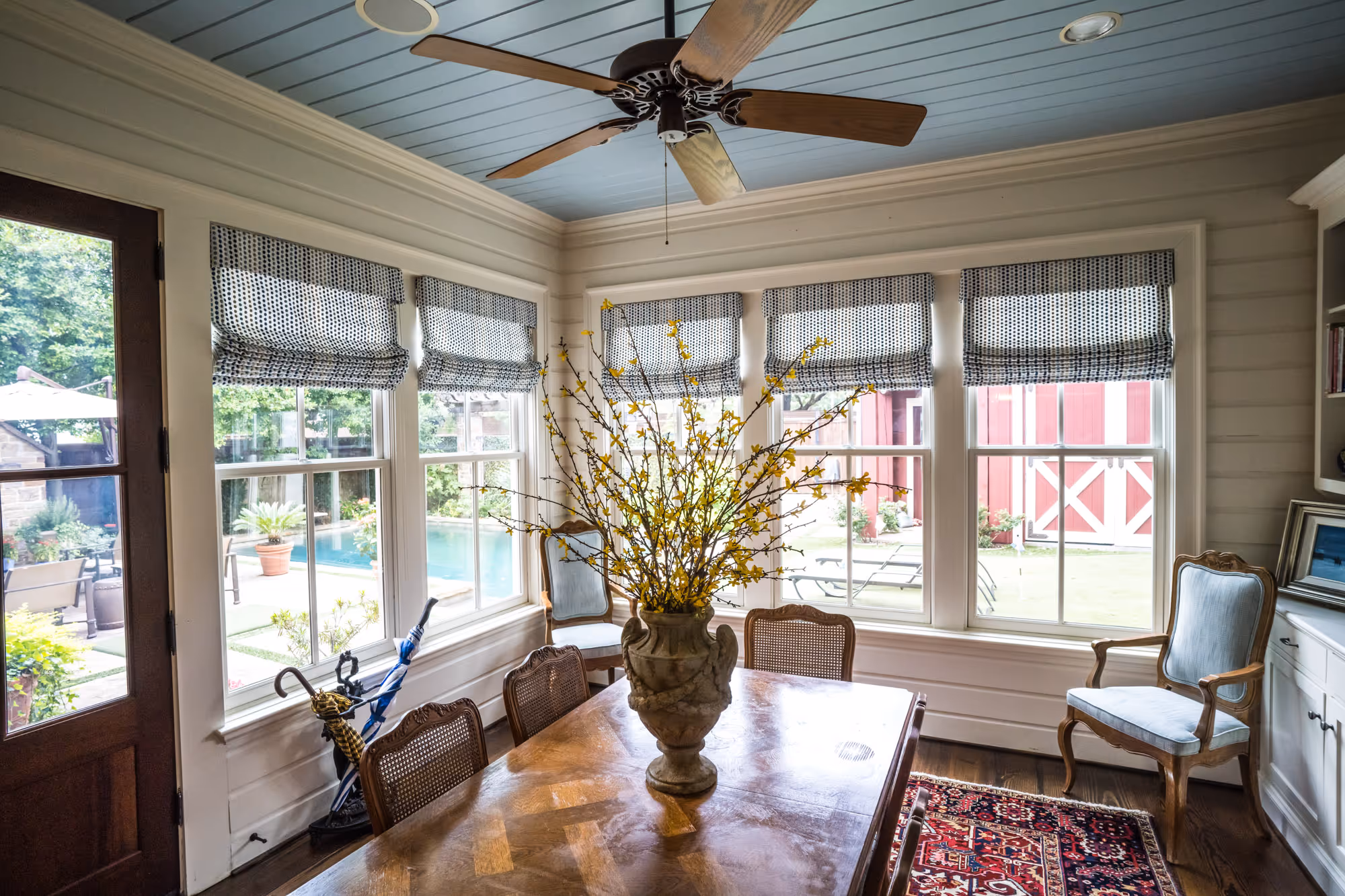 A bright dining room featuring roman shades and a decorative floral arrangement in Dallas, TX