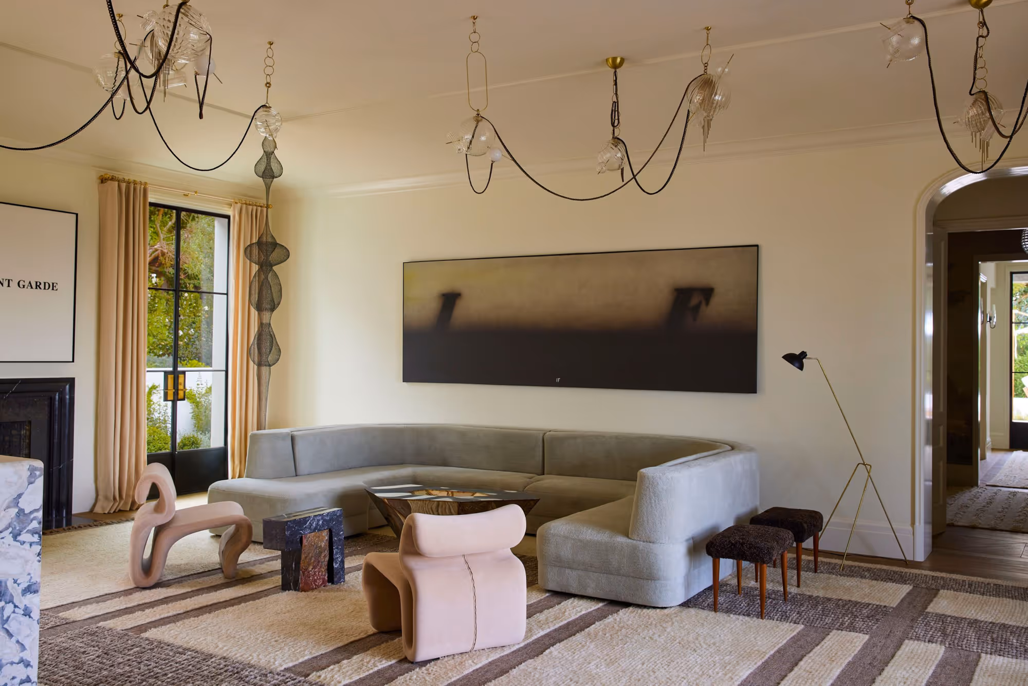 Modern living room in Montecito, CA featuring a curved gray sofa, unique sculptures, and contemporary lighting.