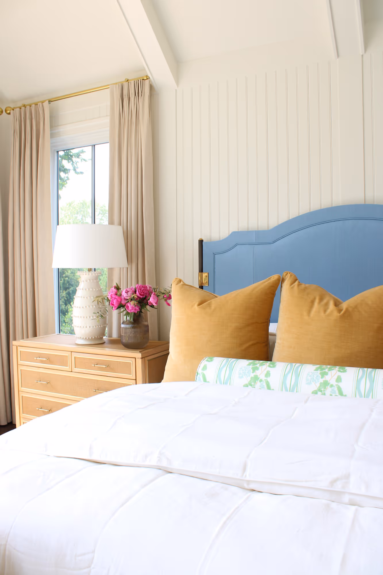 Elegant bedroom featuring blue headboard, beige curtains, and decorative pillows in Arlington, VA.