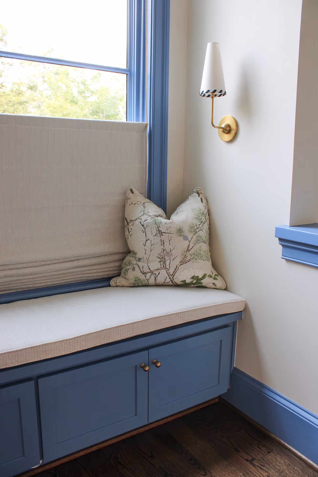 Cozy residential window seat with blue cabinetry, cream cushion, and decorative pillow, located in a stylish home in arlington, va.