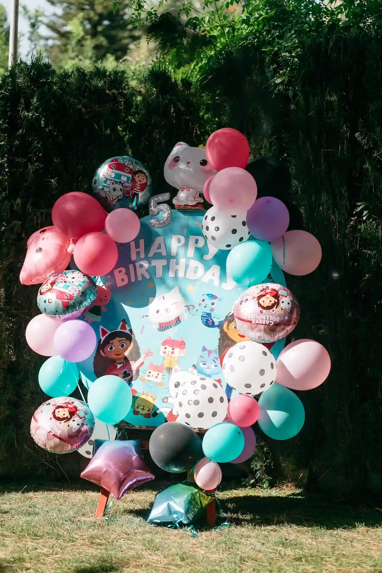 Colorful birthday balloon arrangement with cartoon animals and a 'Happy Birthday' sign outdoors.