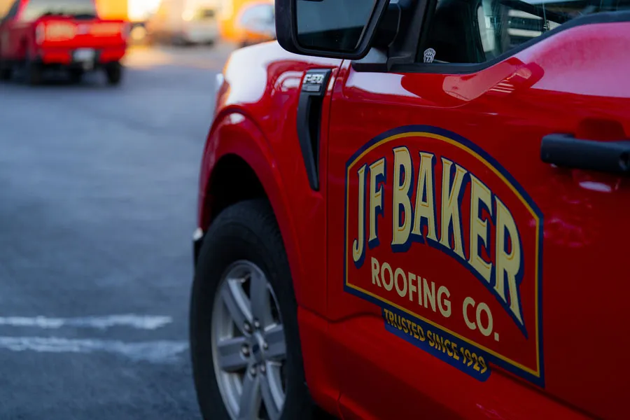 Side view of a red truck with a J F Baker Roofing Co. logo on the door.